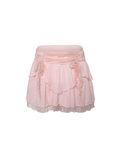 The HARPER MINI SKIRT from TIGERMIST features a pastel pink hue with a ruched waistband. This baby pink mini skirt is designed with soft, delicate fabric, complete with ruffled detailing and an asymmetric hemline. Its sheer outer layer adds a light, airy feel to the design.