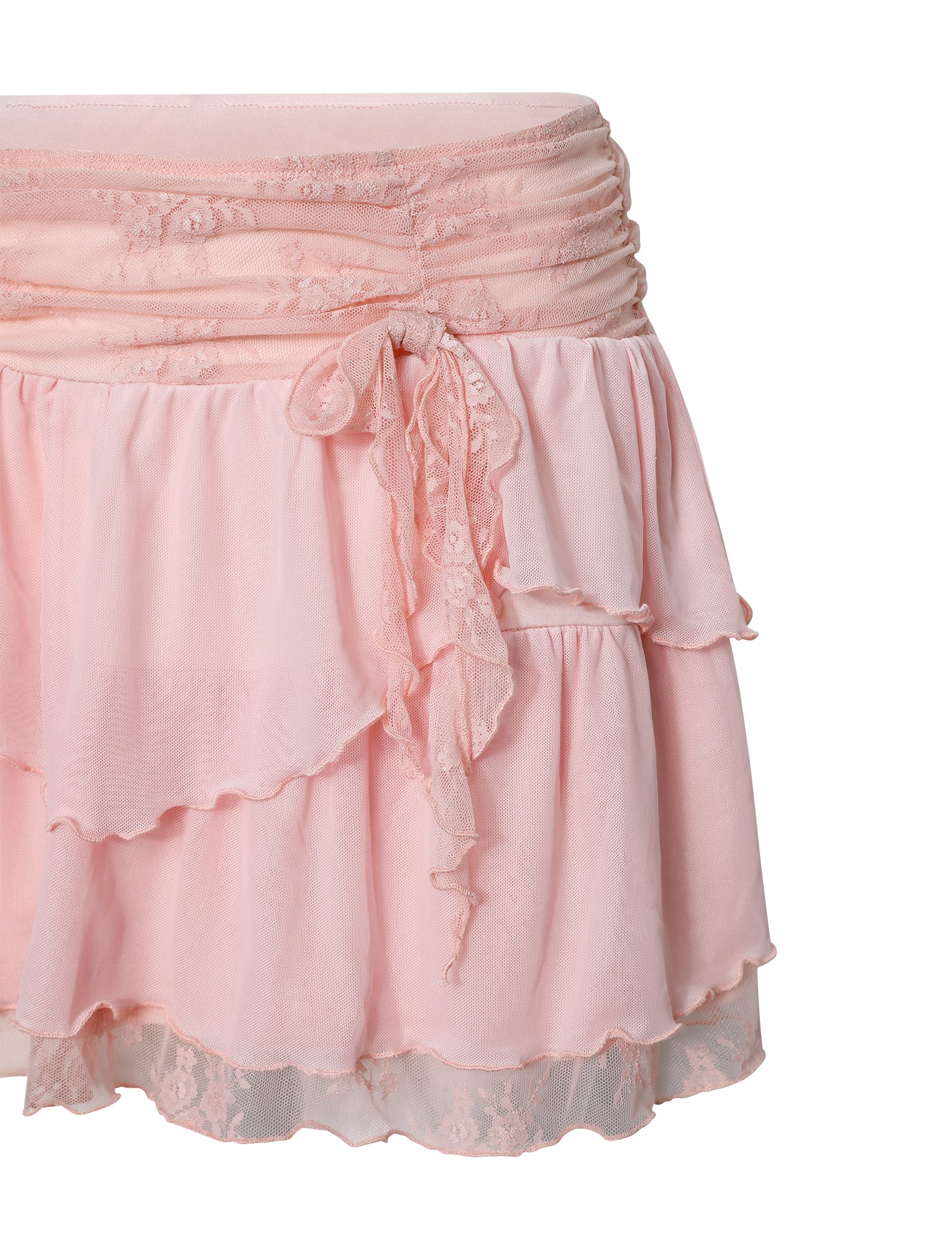 The Harper Mini Skirt in pastel pink from TigerMist features a ruched waistband with lace detailing and an asymmetrical bow. This layered skirt has multiple flowing tiers, creating a soft, feminine look finished with a lace trim at the hem.