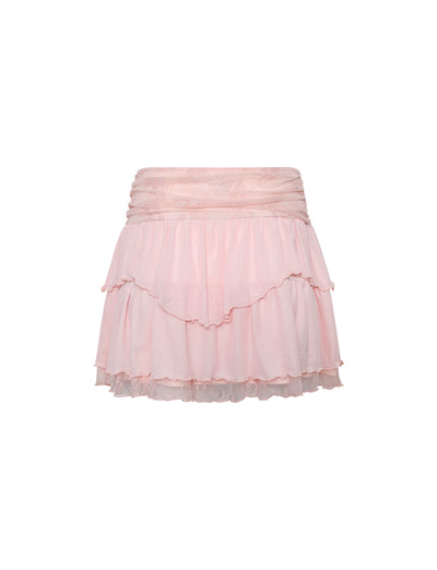 The HARPER MINI SKIRT in pastel baby pink from TIGERMIST features a light pink, tiered design with ruffles and a lace waistband. This mini skirt has multiple layers that provide a flouncy, feminine look. The semi-sheer fabric is adorned with delicate floral embroidery and has a soft, flowy texture.