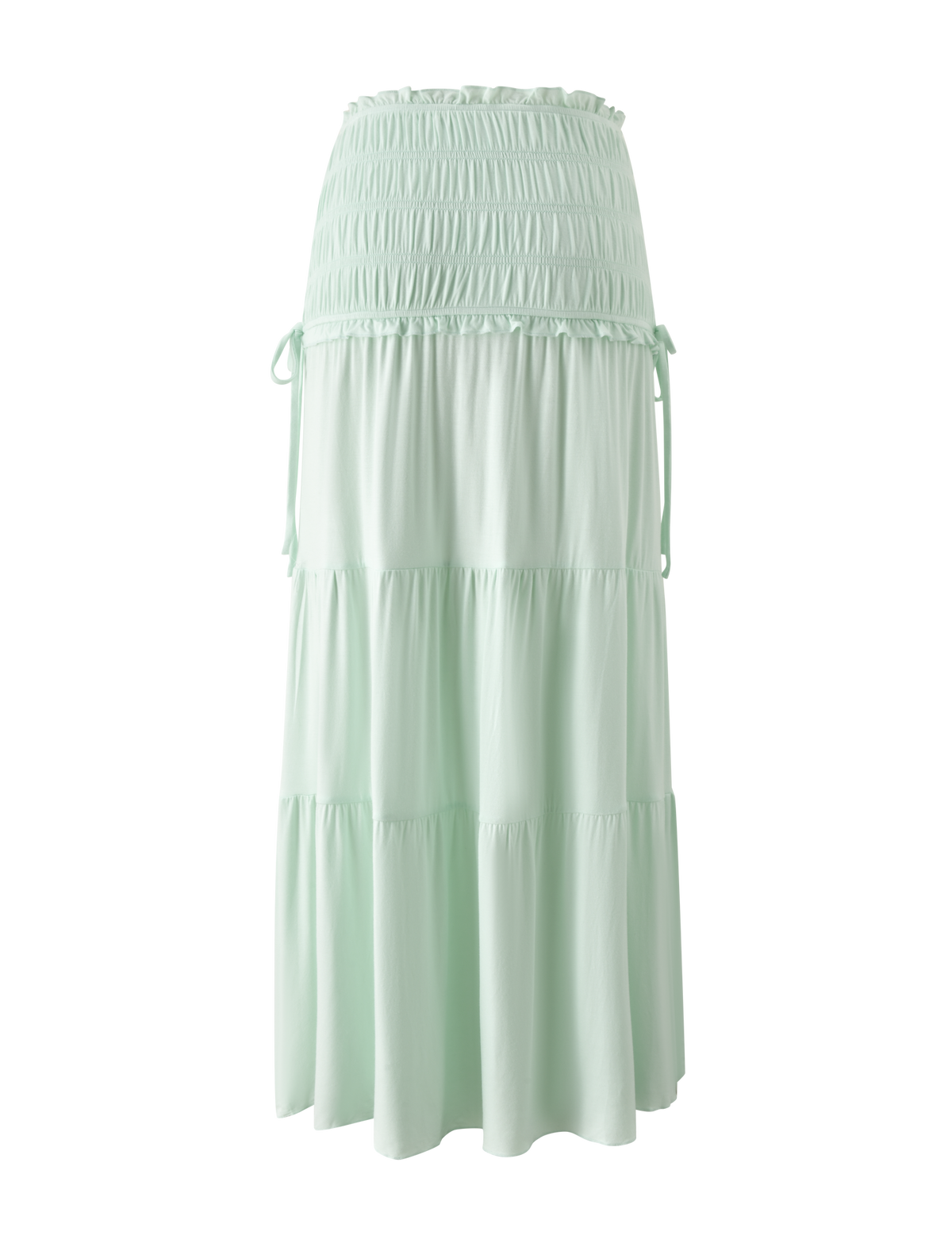 The DENALI MAXI SKIRT in Soft Mint by TIGERMIST is a light mint green maxi skirt made from soft modal fabric, with a smocked waistband, tiered design, and adjustable side ties, shown on a plain white background.