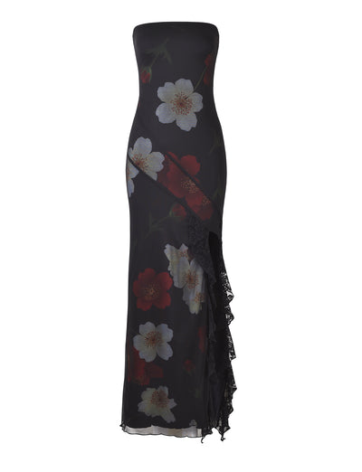 Introducing the THEO MAXI DRESS - RED: MACRO FLORAL by TIGERMIST, a strapless, floor-length black dress intricately adorned with a bold white and red floral pattern. This sophisticated creation features an asymmetrical design complemented by a lace-trimmed slit on the left side, adding an elegant touch to your ensemble.