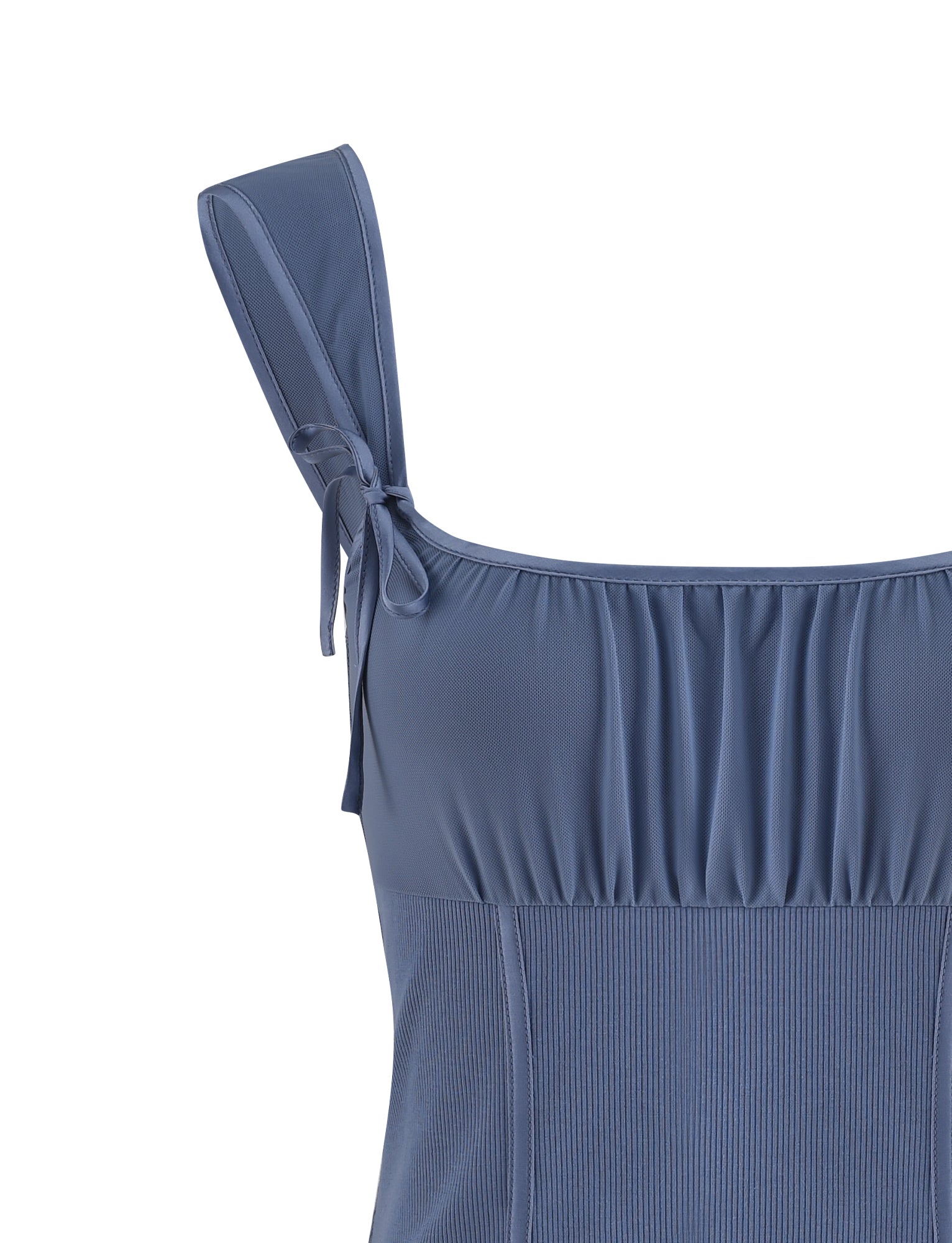 A close-up of the NOEMI TOP - BLUE by TIGERMIST, showcases gathered fabric above the bust and adjustable shoulder straps tied in bows. The dusty blue sleeveless top boasts a ribbed texture from the midsection downwards.