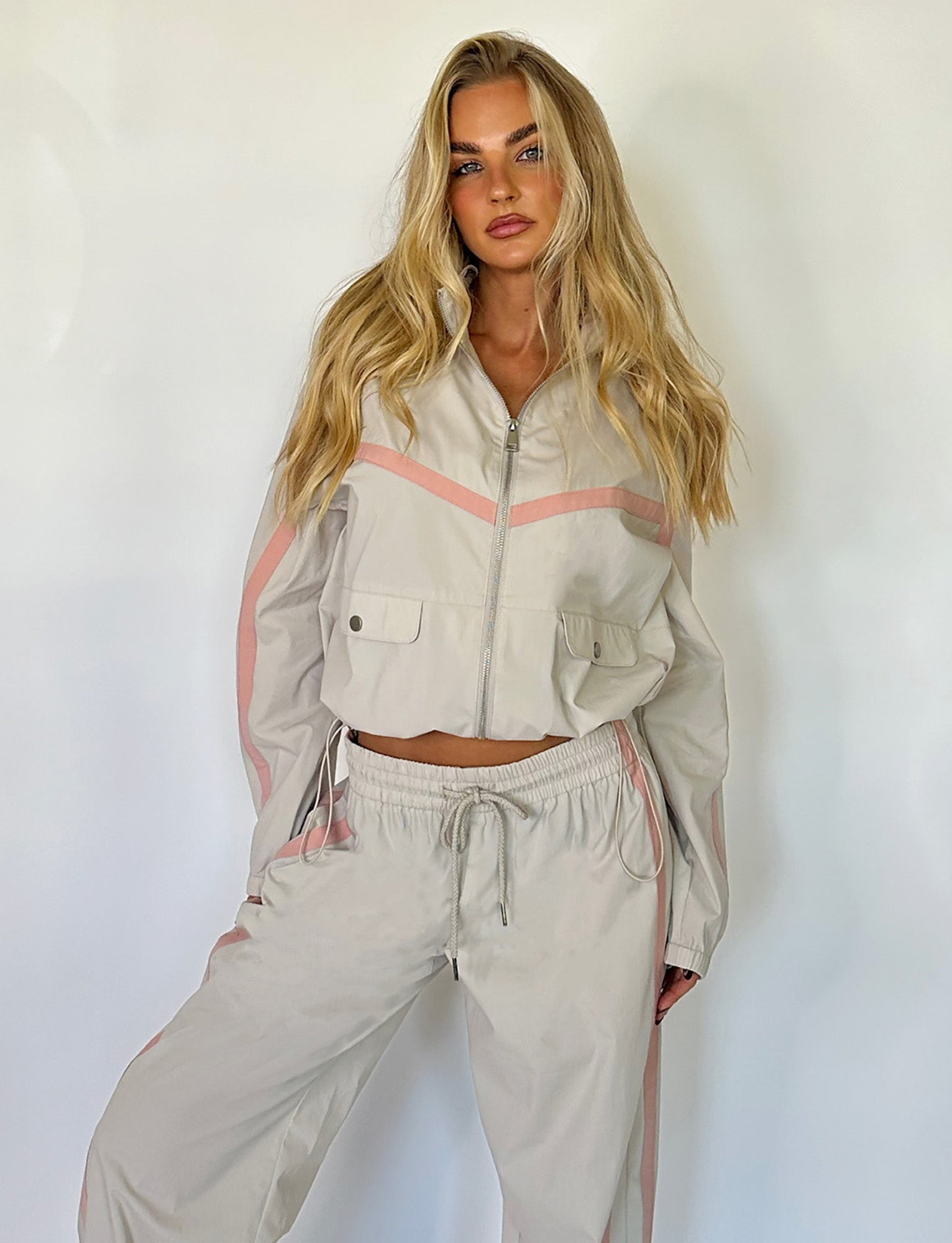 A person with long, wavy blonde hair is wearing the TIGERMIST KAHANNA JACKET in Dove Grey. They are standing against a plain white background, hands at their sides, and looking directly at the camera with a serious expression.