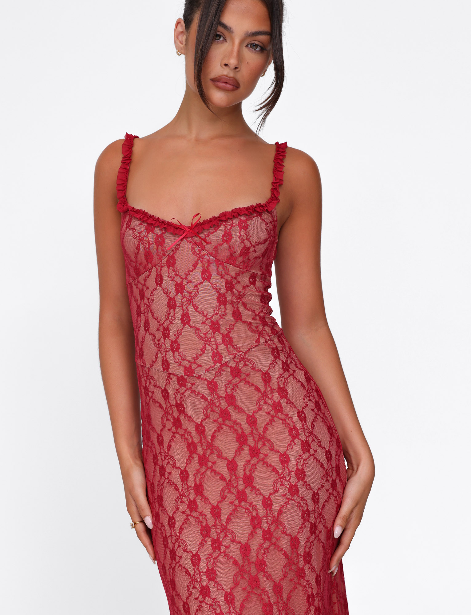 A woman poses against a white background wearing the TIGERMIST DEJA DRESS - RED : BERRY RED, a sheer red lace dress with ruffled straps and a fitted silhouette. Her hair is styled in a loose updo, and she has a neutral expression.