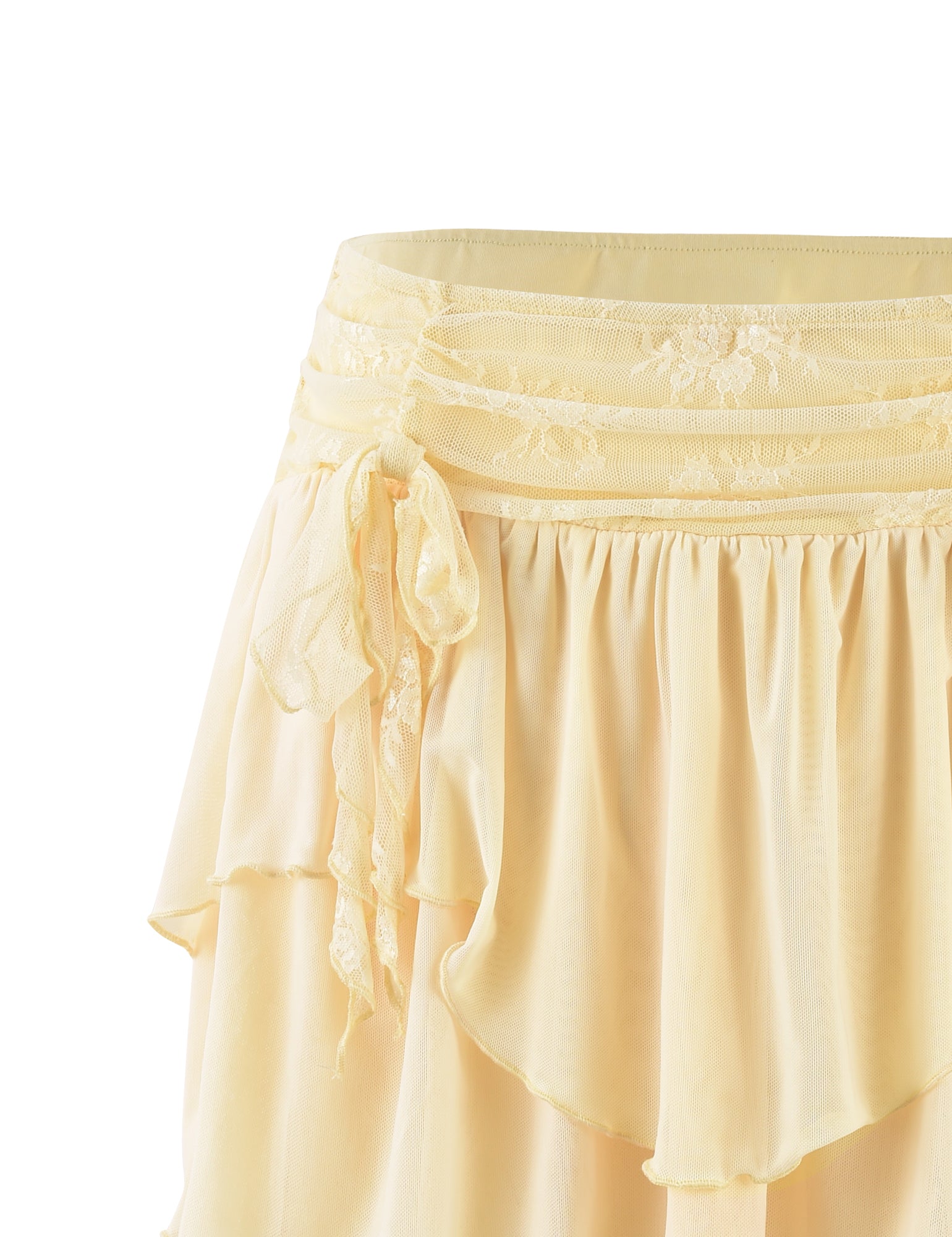 Close-up shot of the HARPER MINI SKIRT - YELLOW : LEMON from TIGERMIST, showcasing layers of soft fabric with delicate lace detailing at the waistband. It features an asymmetrical hemline and a side tie creating a gathered effect. The light material gives it an airy and elegant appearance.