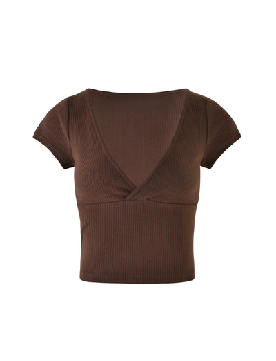 The KAVAT TOP - BROWN by TIGERMIST is a brown, short-sleeved ribbed crop top featuring a deep V-neckline and an overlapping wrap design at the chest. The stretchy, fitted fabric offers a snug and stylish look.