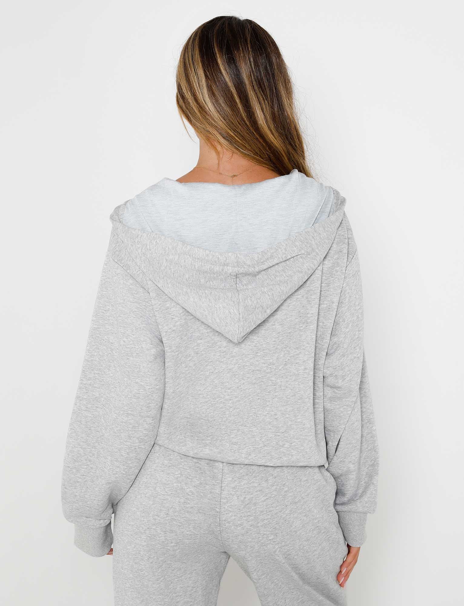 Rear view of a person with long, light brown hair, wearing the ALISH HOODIE - GREY : GREY MARLE and matching sweatpants from TIGERMIST. The person is standing against a plain white background.