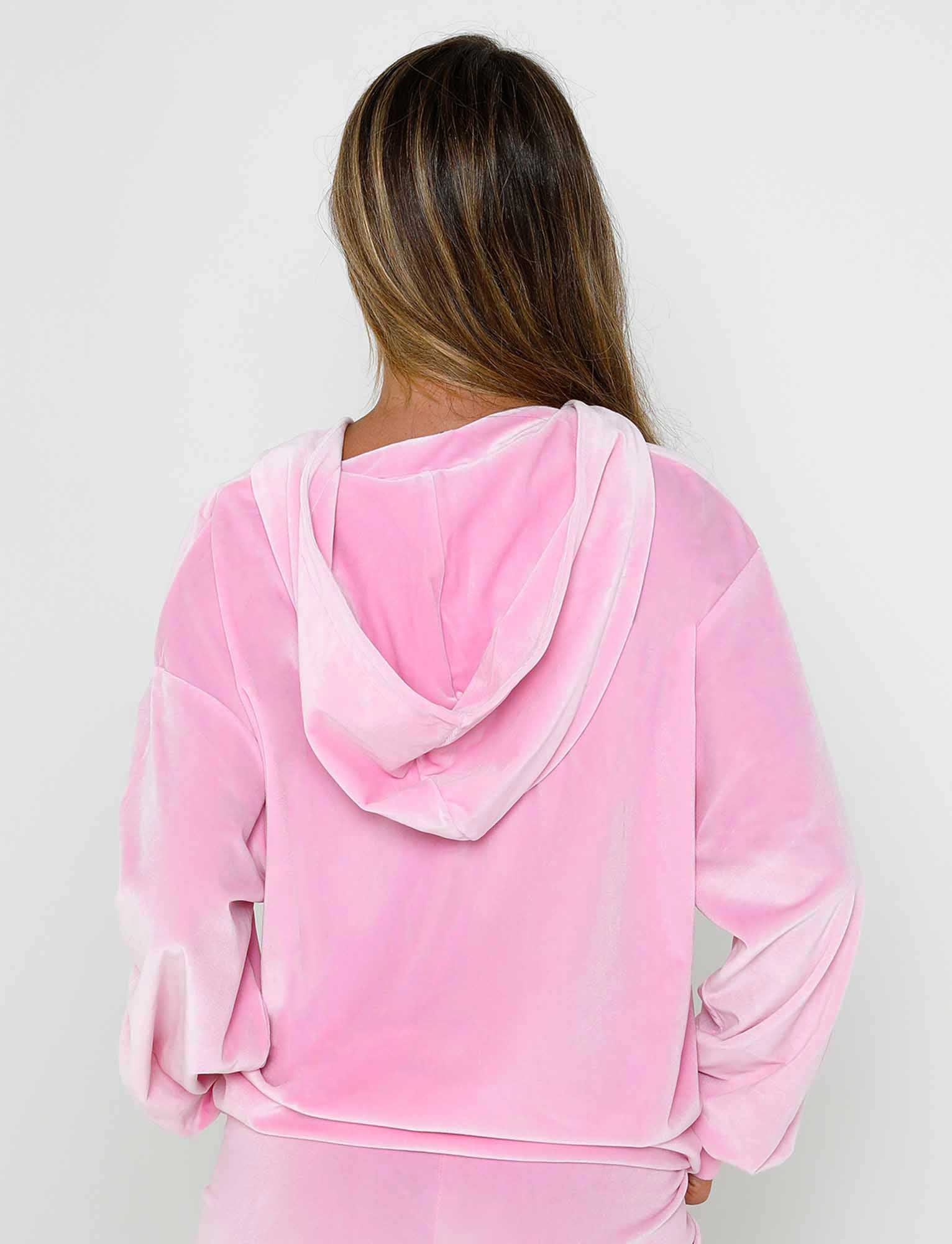 A person with long, straight hair is shown from the back, wearing the ERICKA HOODIE - PINK : BABY PINK by TIGERMIST. The image highlights the soft texture and relaxed fit of this velour hoodie against a plain white background.
