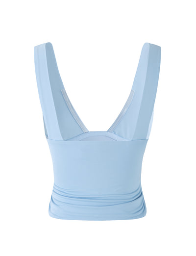 A baby blue LUNARIA TOP by TIGERMIST featuring wide shoulder straps and a low V-neck back design. The fabric is smooth and stretchy, providing a fitted look around the torso, with a slightly ruched detail at the bottom of the back panel.