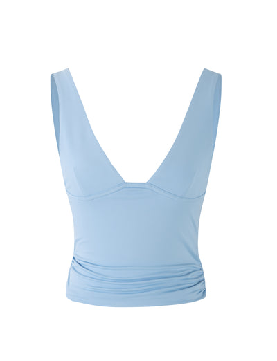 The LUNARIA TOP in BABY BLUE by TIGERMIST features a light blue, sleeveless crop top design with a deep V-neck. Its soft fabric is slightly gathered around the waist, providing a fitted look and smooth texture that make it ideal for both casual and semi-casual occasions.