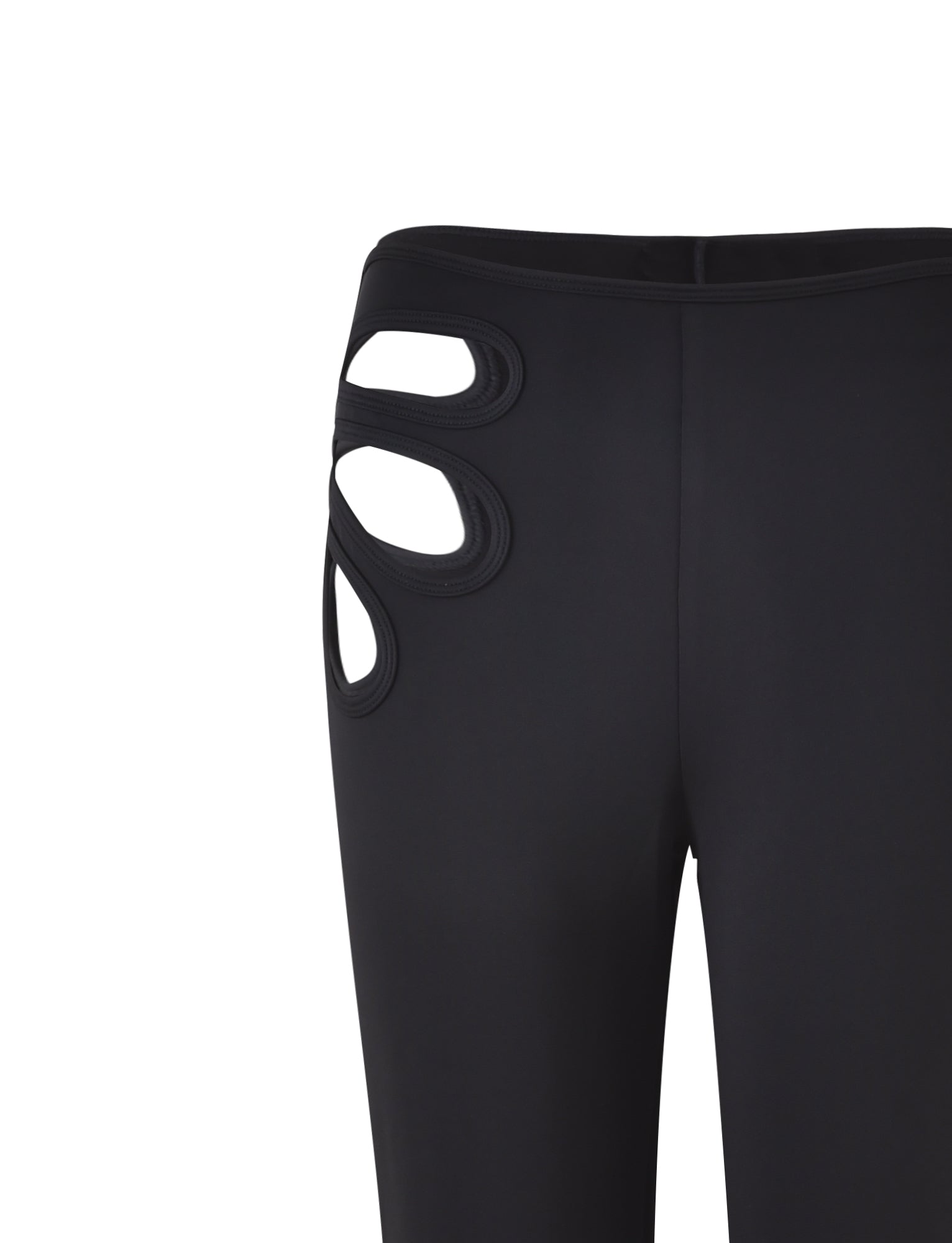 Close-up of a pair of black KATO PANT leggings by TIGERMIST, featuring unique cut-out detailing on the left hip area. The cut-outs form an interesting design, revealing a portion of the wearer's skin underneath. The fabric appears smooth and stretchy.