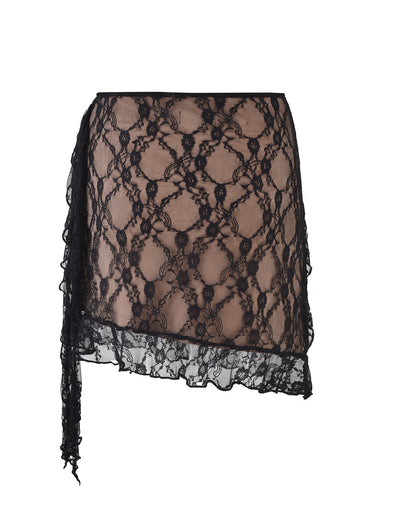 The STORMI LACE SKIRT - BLACK from TIGERMIST features an asymmetrical hem and partial wrap design. This black lace skirt showcases a delicate floral lace pattern overlaying a nude lining, creating a sheer effect throughout the garment.