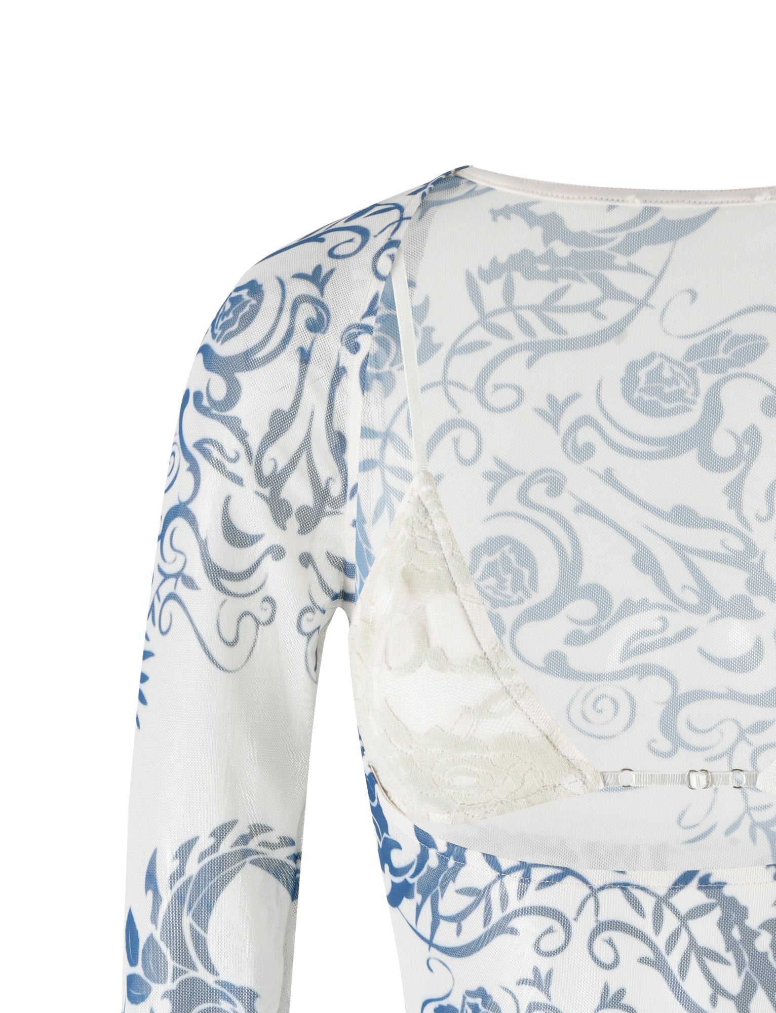 A close-up of the TIGERMIST CHRISTY Mesh Long Sleeve Top - Blue Tattoo Print, showcasing its intricate blue floral patterns on a sheer white material. The top is styled to reveal a white lace bra underneath, with a focus on the right shoulder and upper back area.