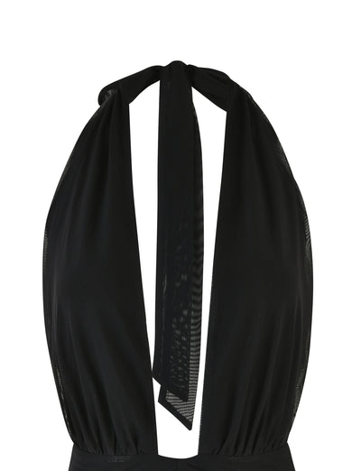 The HALIMA MINI DRESS - BLACK by TIGERMIST is a black halter neck mini dress featuring a deep V-neckline with a tie at the back of the neck. The lightweight material is slightly gathered under the bust, creating an elegant silhouette. The dress is displayed on a white background.