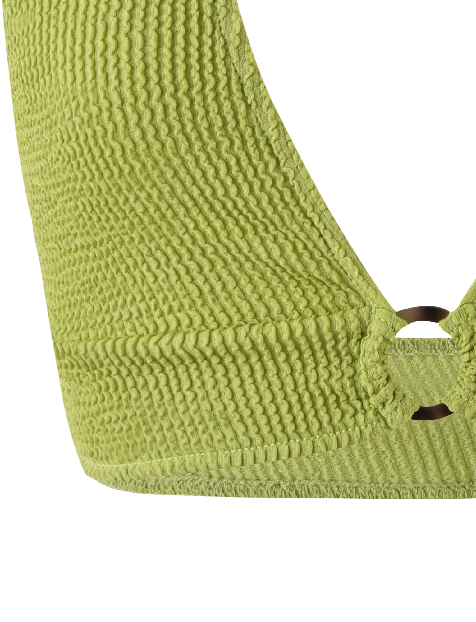 Close-up of the textured green fabric of the NEERA TOP - GREEN : LIME GREEN by TIGERMIST, featuring a cutout detail and a metal ring. The ribbed, slightly wavy pattern of the fabric gives it a tactile appearance. This garment is part of a top.