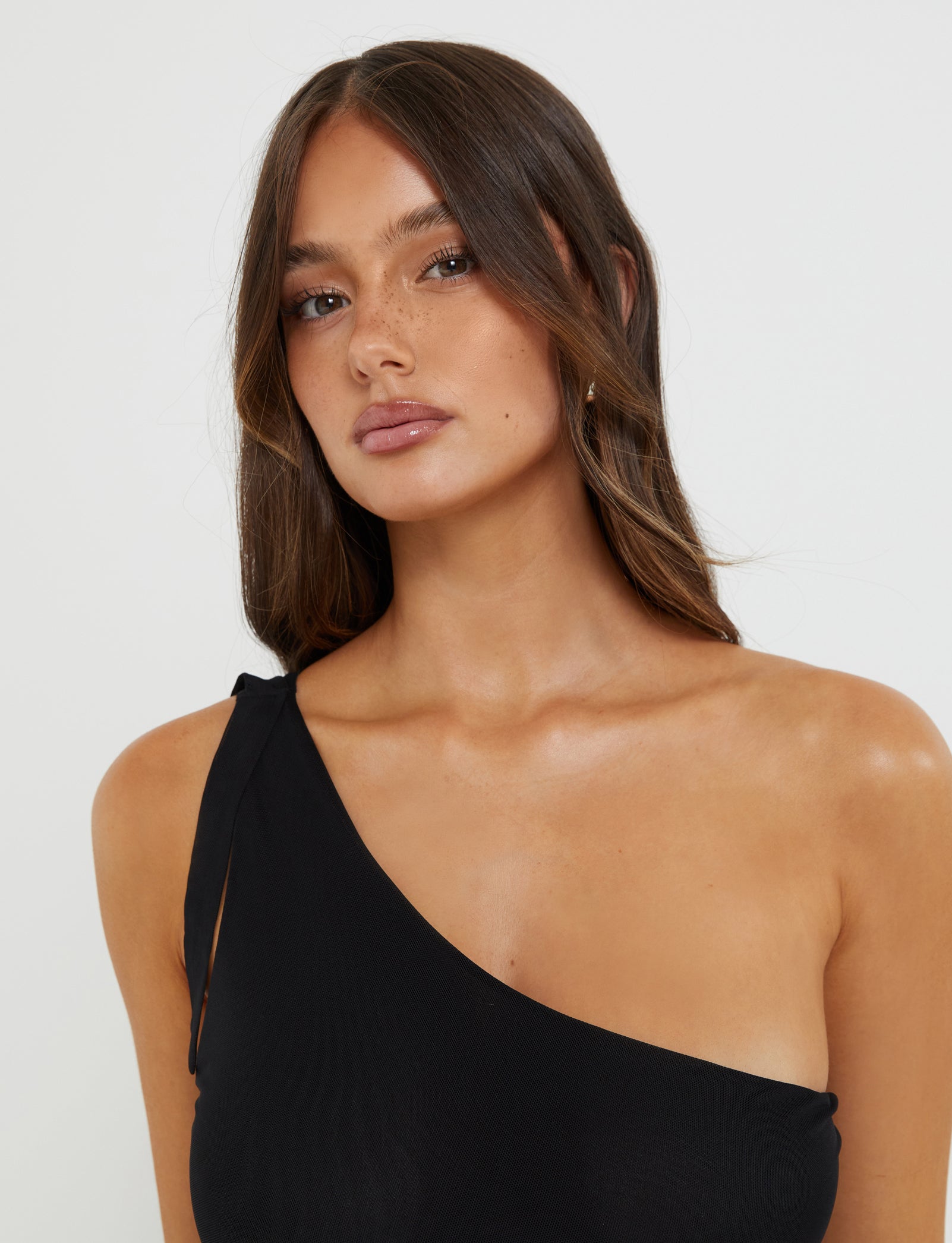 A person with long brown hair is posing against a plain background. They are wearing the DEANNA TOP - BLACK from TIGERMIST and looking directly at the camera with a neutral expression.