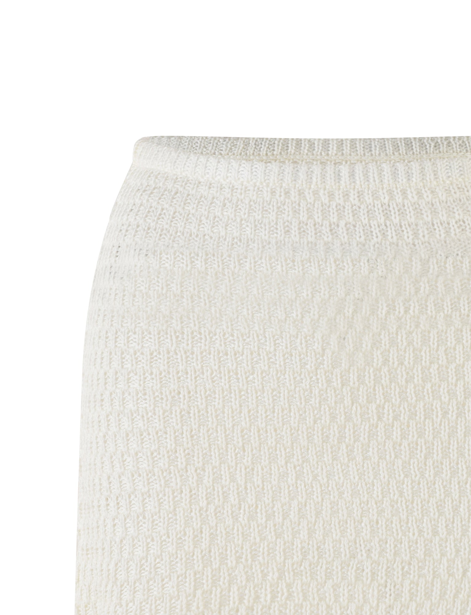 Close-up image of a textured white knit fabric. The photo captures the intricate pattern of what appears to be TIGERMIST's JANAI SKIRT in WHITE : CREAM, displaying its detailed weave and soft appearance. The fabric suggests it could belong to a low-rise elasticated waist mini length skirt with a subtle, repetitive design.