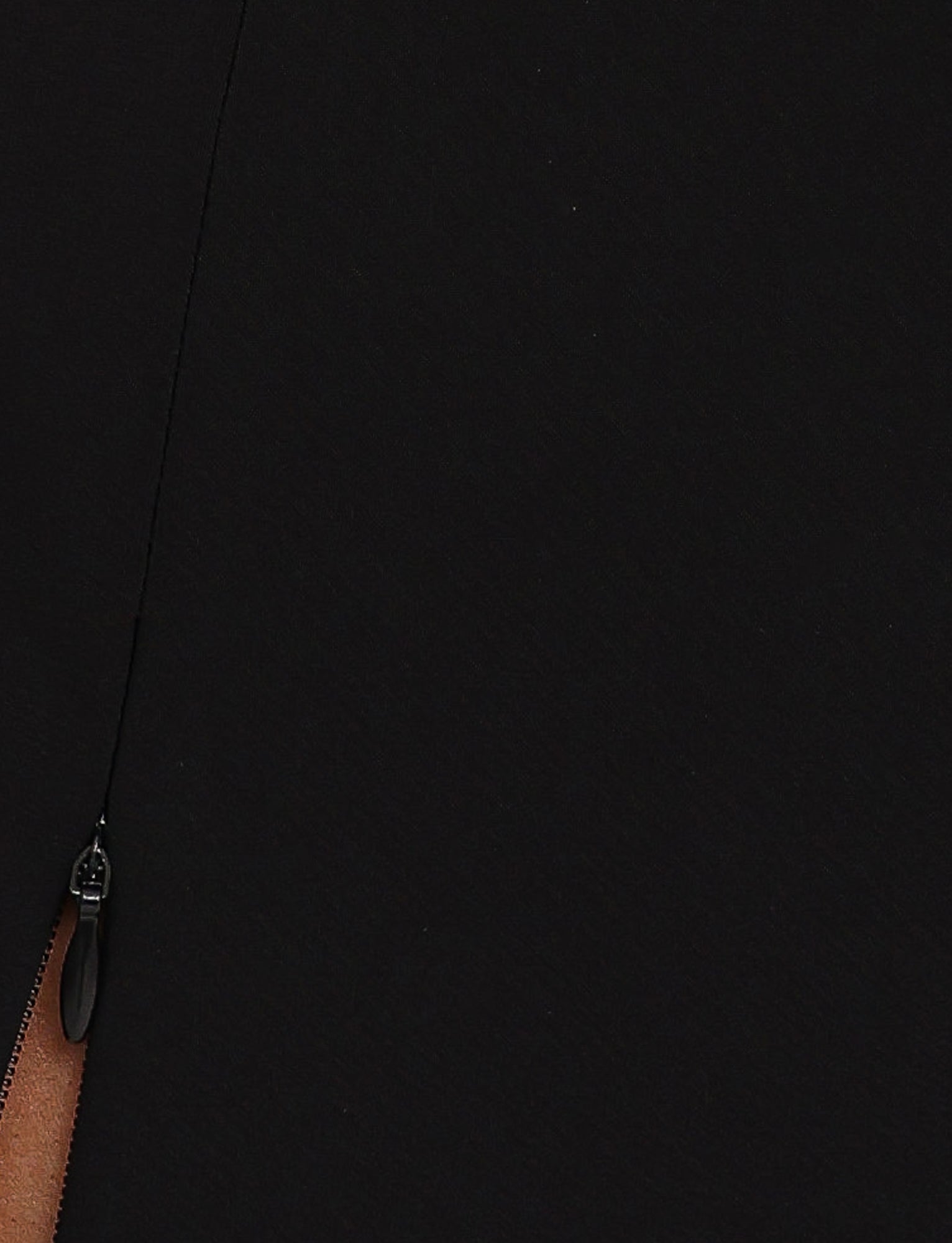 Close-up of the black fabric from the DAMIRA SKORT - BLACK by TIGERMIST, featuring a partially visible zipper on the left side. The metal pull tab and some stitching detail of the zipper are clearly shown.