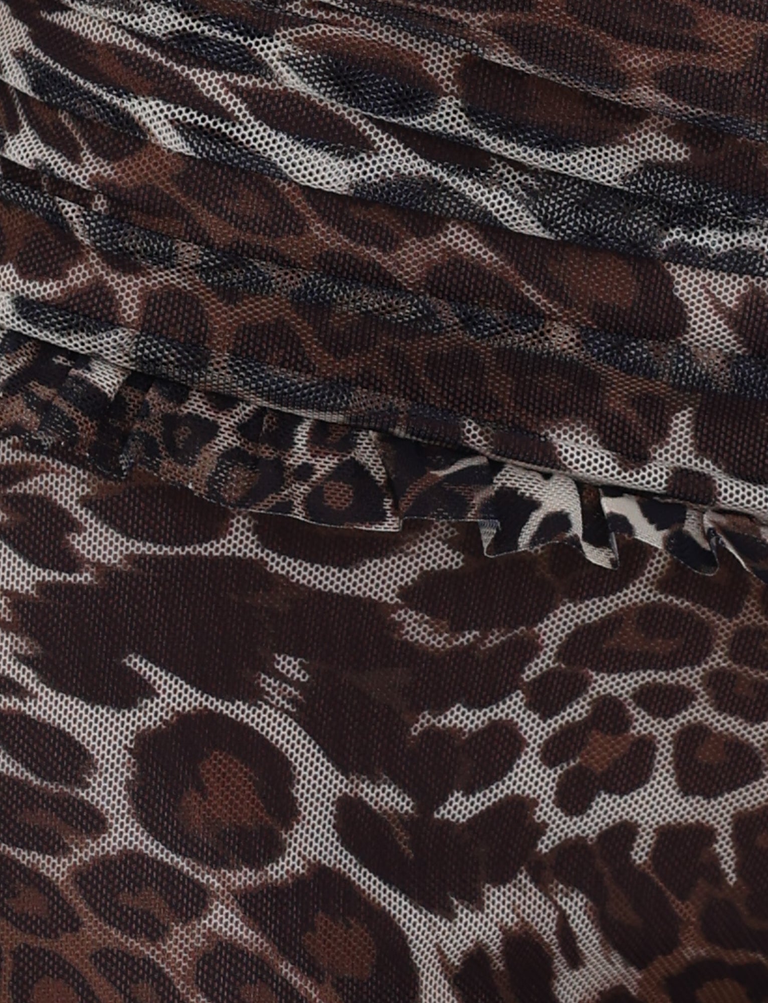 A close-up of the GINNY SHORT - NEUTRAL by TIGERMIST reveals its stunning leopard print design, highlighted with intricate ruffle details. The fabric beautifully captures various shades of brown and black, mimicking the spots and textures typical of a leopard's fur.