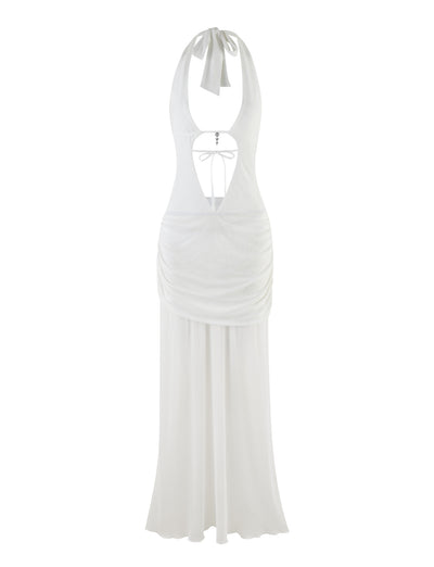 The ESHA MAXI DRESS - WHITE by TIGERMIST is a sophisticated halter-neck piece featuring a plunging neckline, open back, and ruched detailing at the waist. Designed with a flowing skirt, it ties at the neck and back to create an elegant maxi-length silhouette.