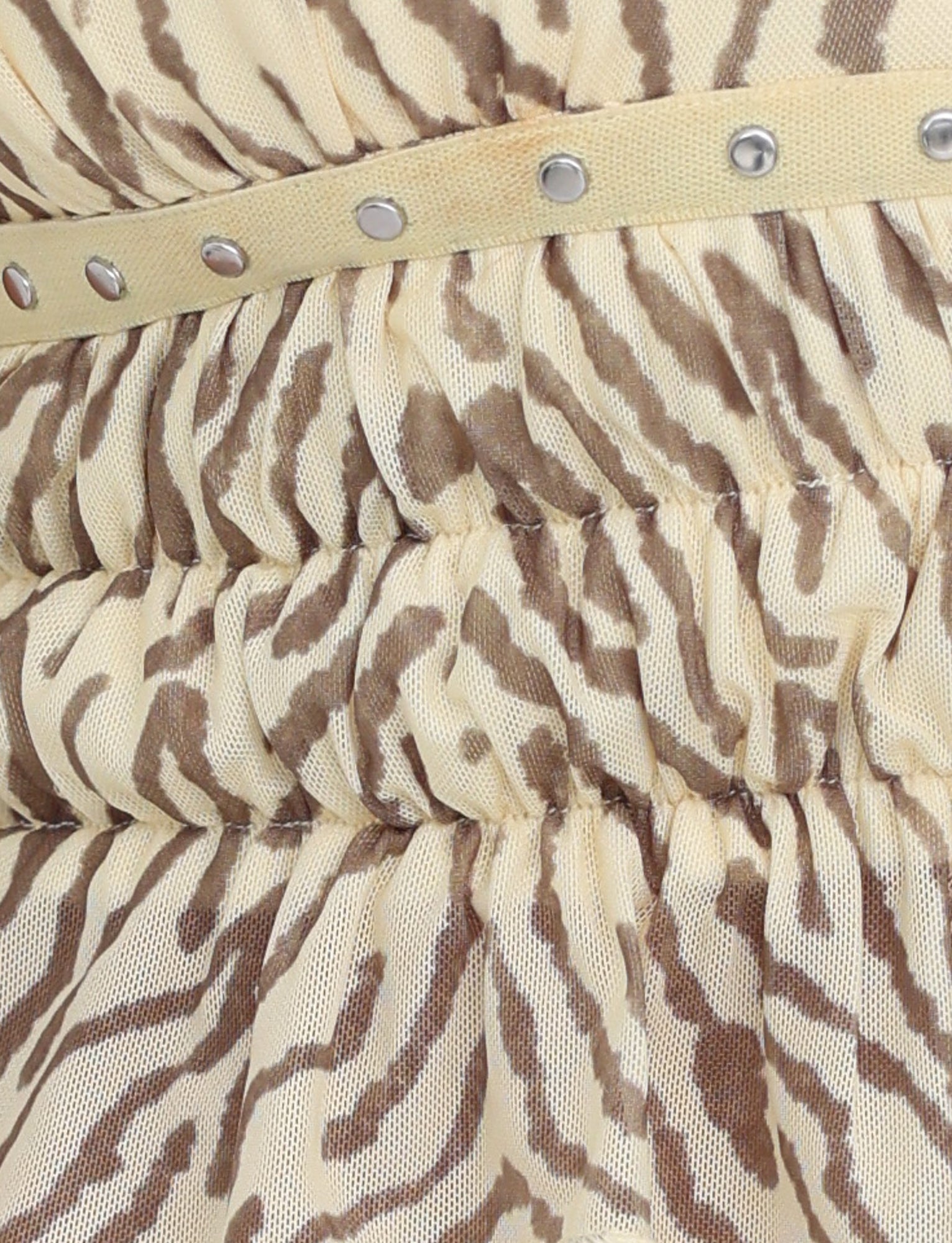 Close-up of the RUMER TOP - YELLOW : ZEBRA by TIGERMIST featuring a waistband adorned with metal studs. The fabric appears to be gathered underneath the waistband, creating a ruched effect and ending in a stylish ruffled hem.