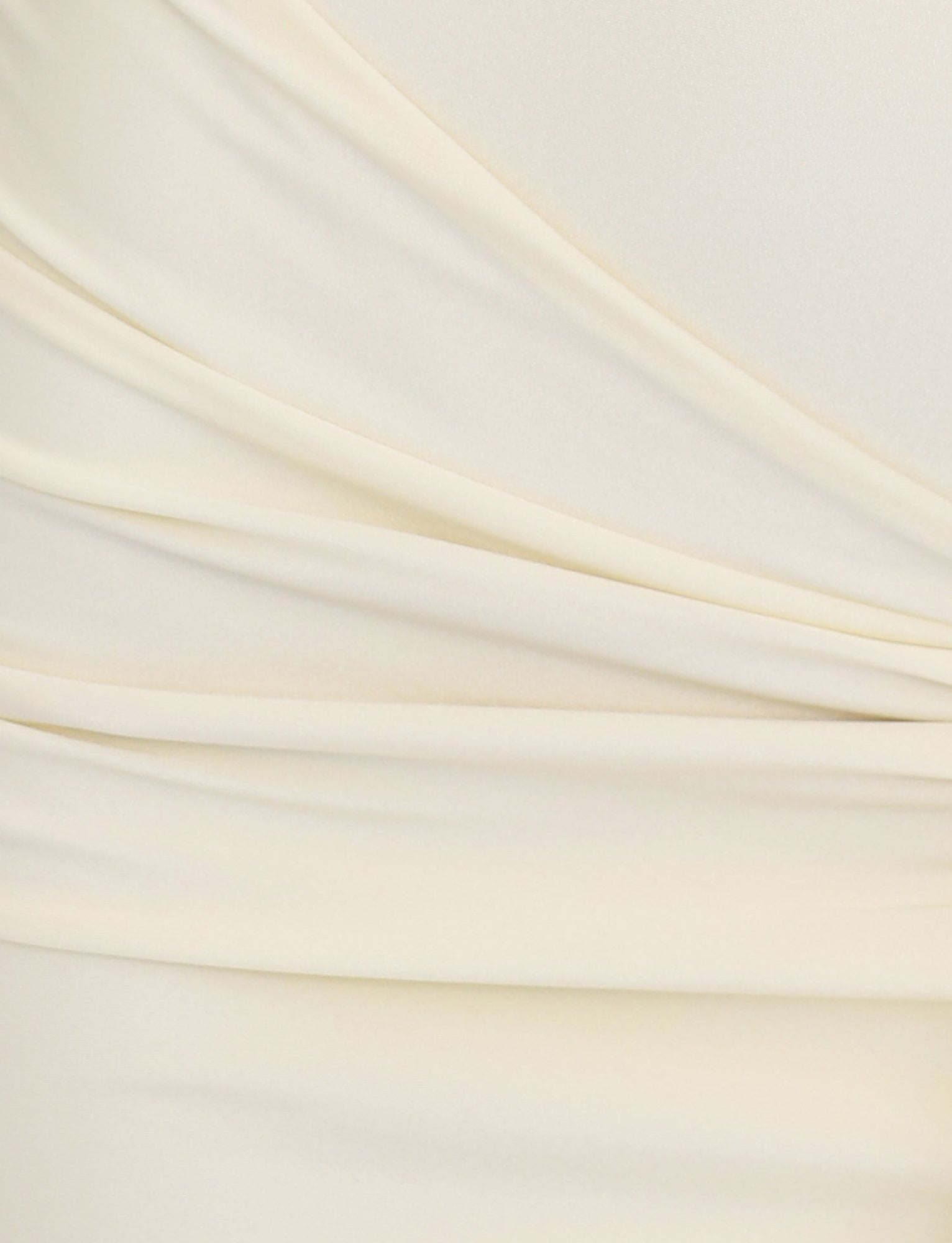Close-up of soft, butter-yellow fabric from the ELYSIA DRESS by TIGERMIST. The material exhibits gentle, overlapping folds and draping with a smooth, slightly shiny texture, creating an elegant and refined appearance reminiscent of shimmer jersey fabrication.