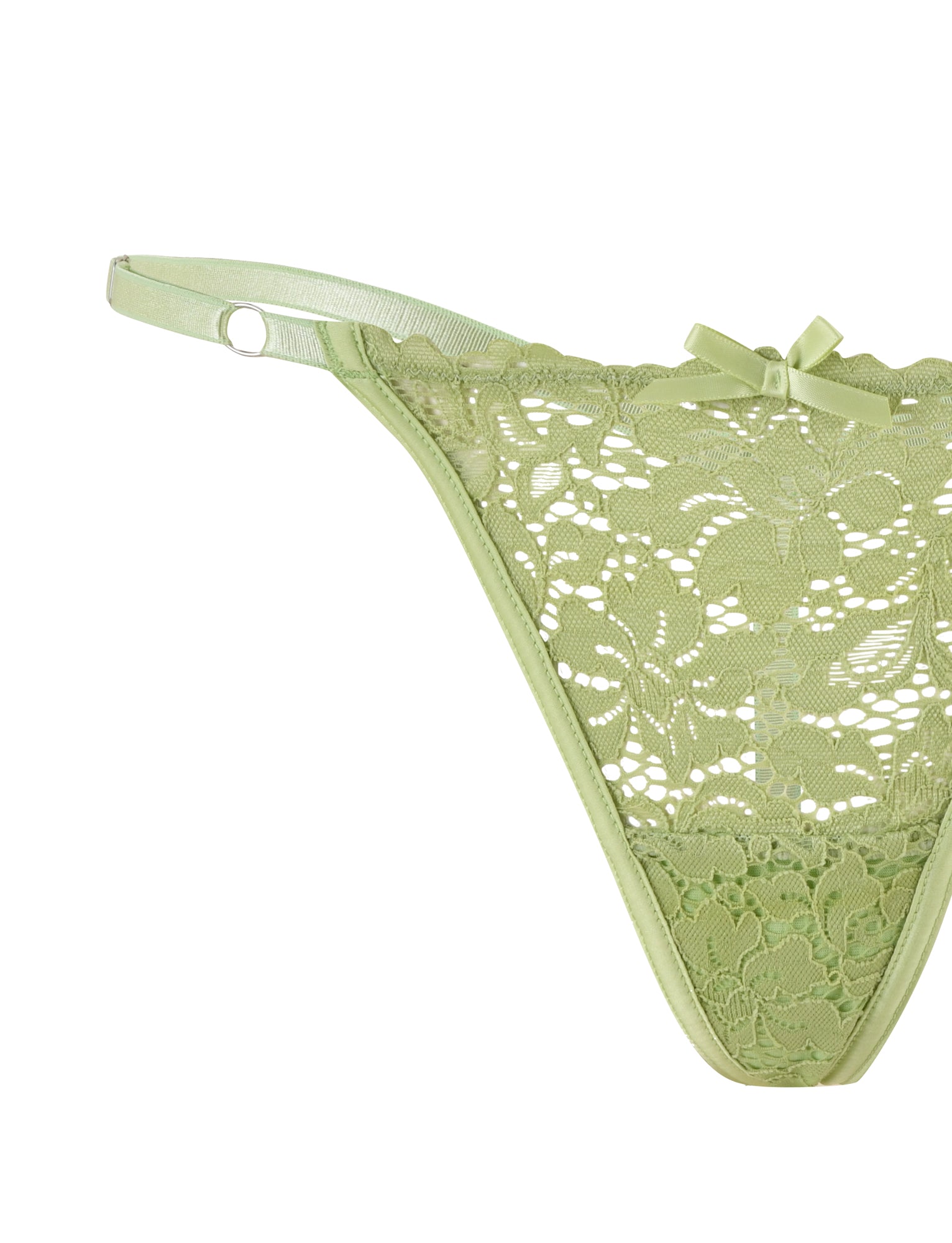 A close-up of the Tigermist "Rosalyn Set - Green" light green lace thong with floral patterns, featuring delicate lace detailing and a small decorative bow at the waistband. The thong includes a thin, adjustable waistband adorned with a circular metal ring on one side. This piece is part of a matching bra and g-string set. The background is plain white.