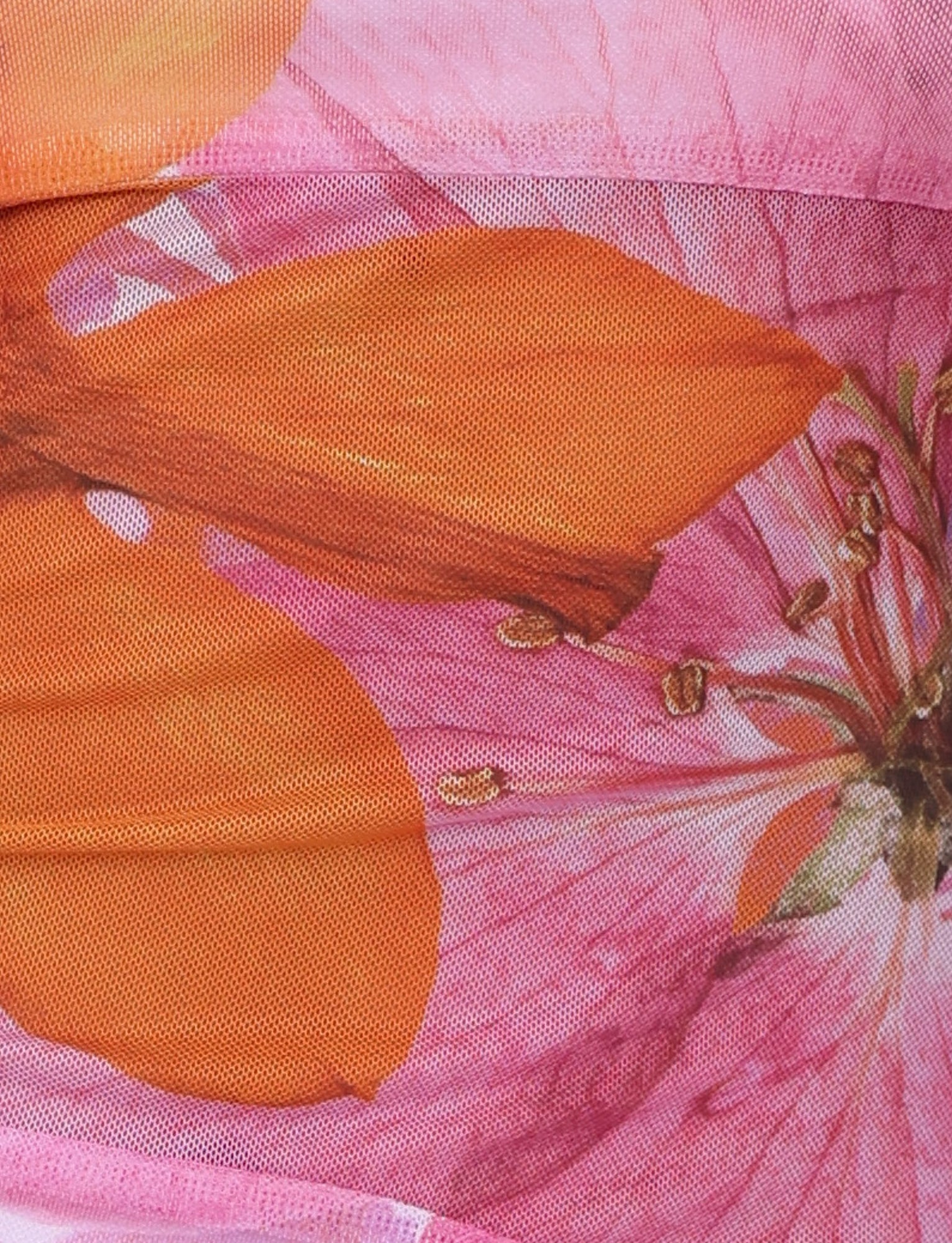 Close-up of fabric with a vibrant floral print, reminiscent of the TIGERMIST Morgan Dress in Pink from the By Poppy Summer collection. The pattern showcases large, detailed flowers in shades of pink and orange, with clearly visible petals and stamen. The fabric appears slightly textured, enhancing the intricate design.