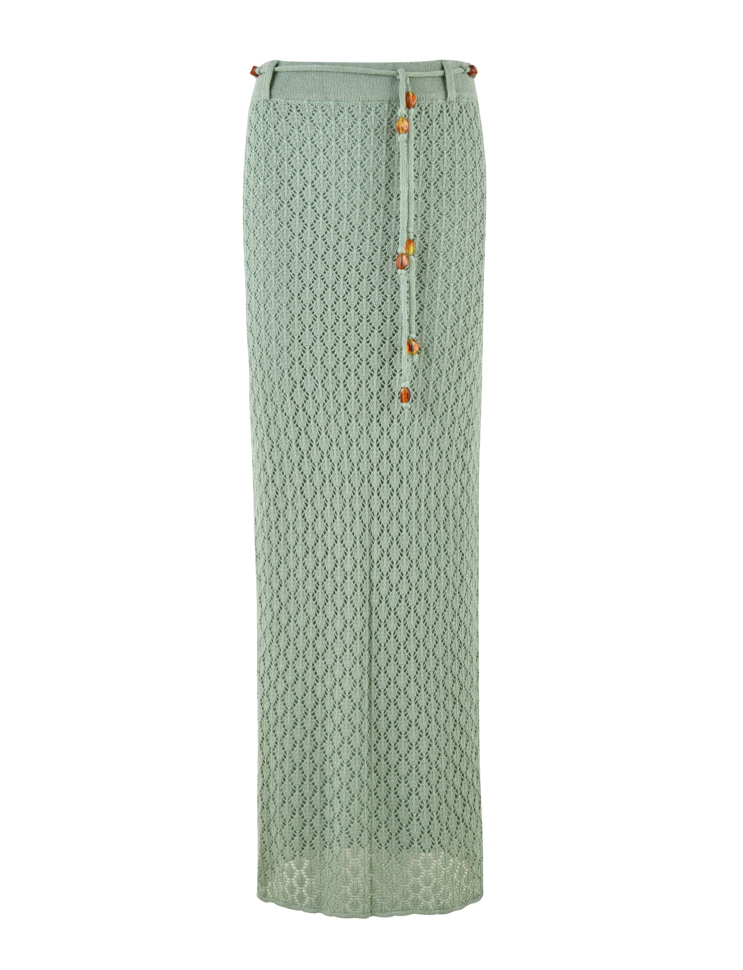 The COLLINA SKIRT - GREEN by TIGERMIST is a full-length, fitted crochet skirt in light green. This elegant piece showcases a delicate, intricate pattern and includes a thin, matching waistband string adorned with small geometric beads.