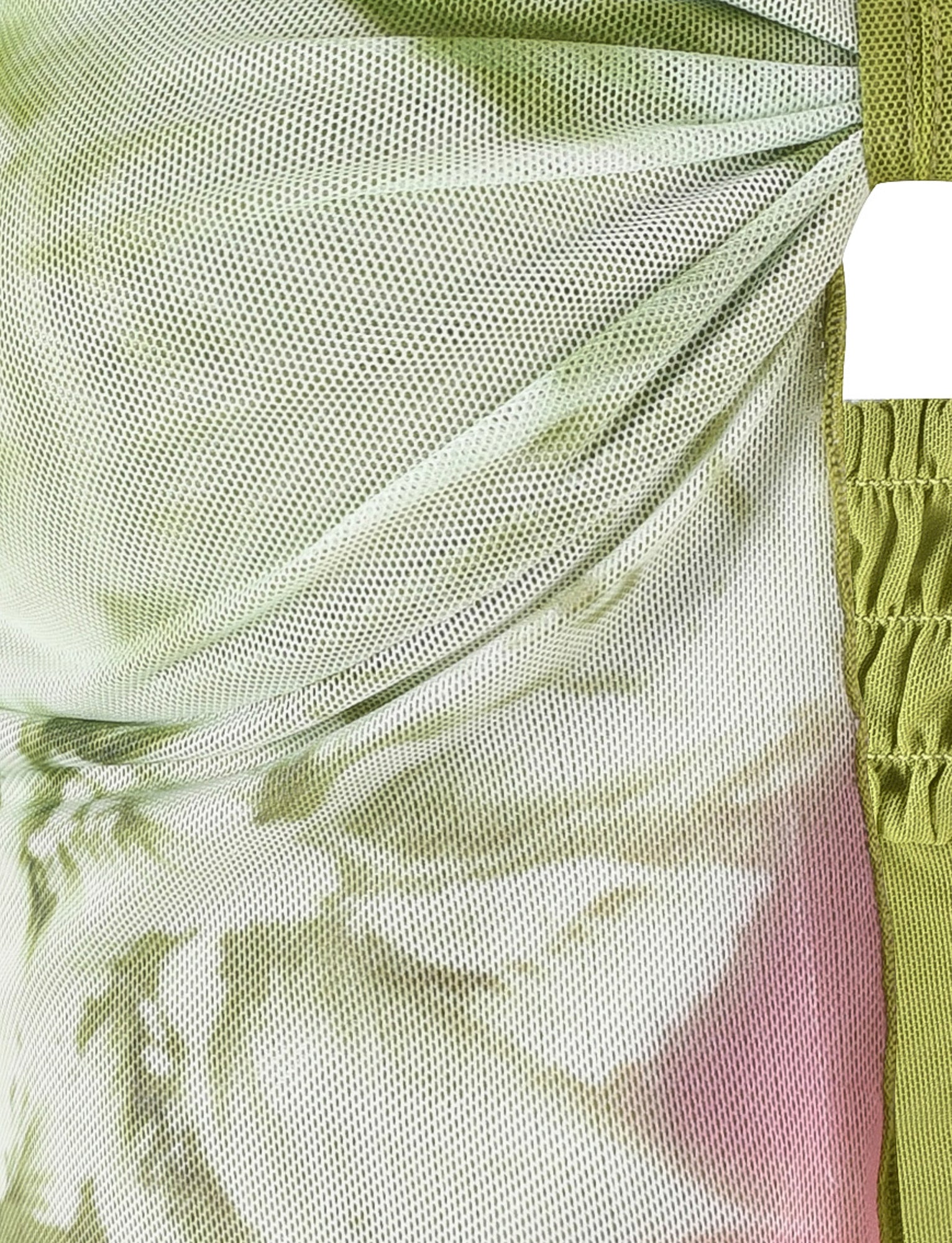 A close-up of the WAVERLY TOP in green with a floral stripe pattern by TIGERMIST, showcasing its stretchy mesh fabric with a blend of green, white, and pink hues. The fabric is gathered and ruched in certain areas, creating intricate folds and a textured appearance. A crop-length green strap is visible on the right side.