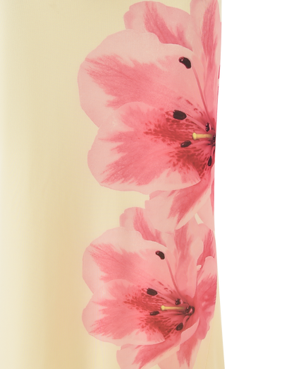 Two large pink flowers with dark centers and yellow stamens bloom across the soft yellow LILLIAN SKIRT by TIGERMIST, making it a perfect floral statement piece.