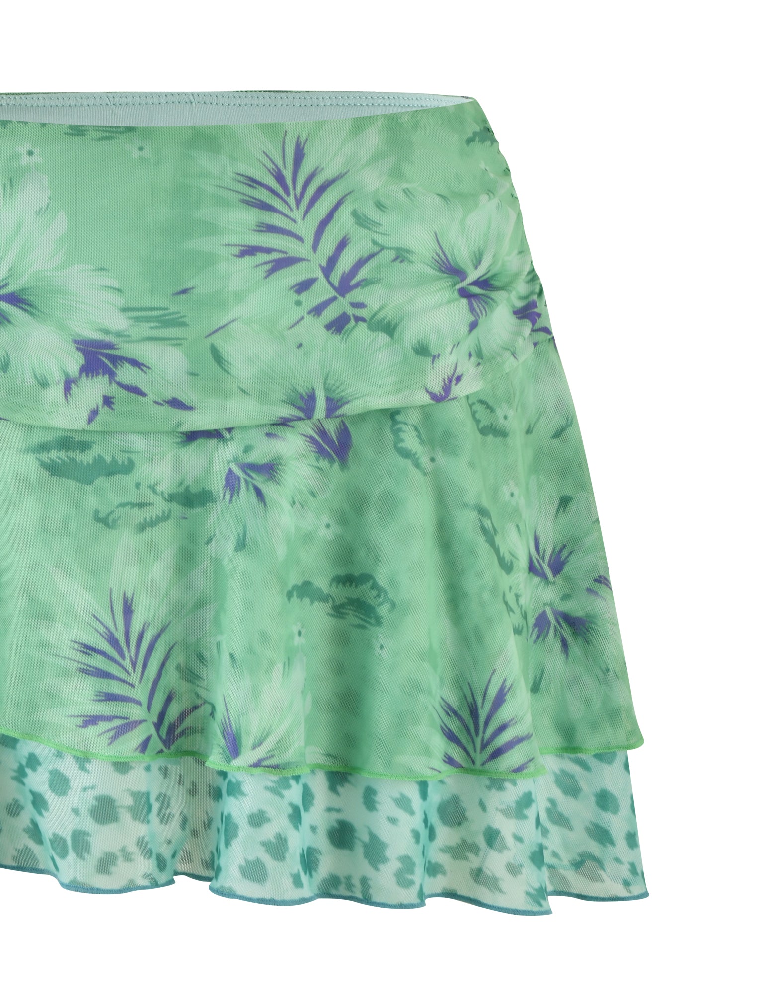 The SAIGE SKIRT from TIGERMIST features a green floral pattern with layered details and a ruffled hem. This skirt showcases a harmonious blend of light and dark green shades adorned with purple flowers and leaves, along with subtle animal prints. Crafted from high-stretch fabric, the material is light and flowy, making it an ideal choice for casual or summer wear.