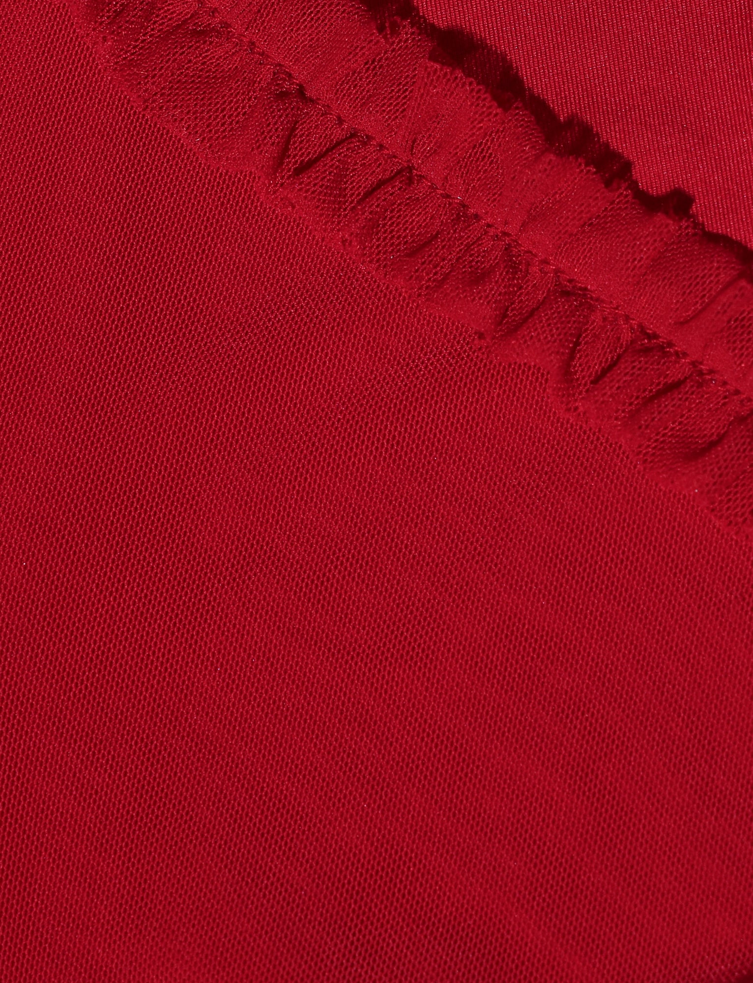 Close-up of a vibrant red fabric with a textured, ruffled border at the top. The smooth fabric contrasts with the detailed stitching and ruffles, adding visual interest to the RAYLA MINI DRESS - RED by TIGERMIST. The fitted silhouette and mini length ensure it makes a statement wherever you go.