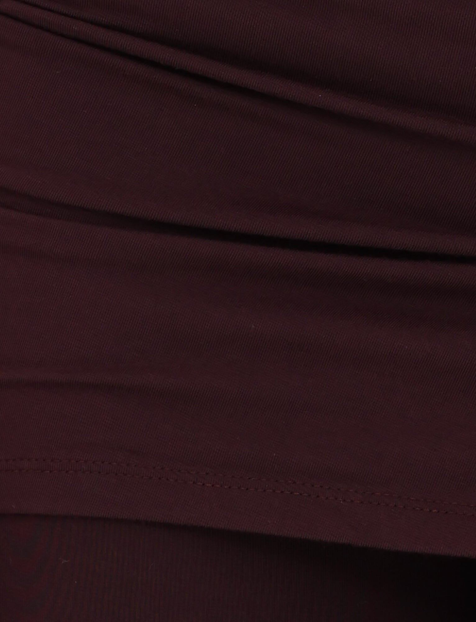 A detailed view of the LEILANI PANT - BROWN : CHOCOLATE from TIGERMIST highlights the visible stitching and folds, indicative of apparel. The fabric has a smooth texture with a bit of elasticity, suggesting it's made from high-stretch material ideal for comfort and fit.