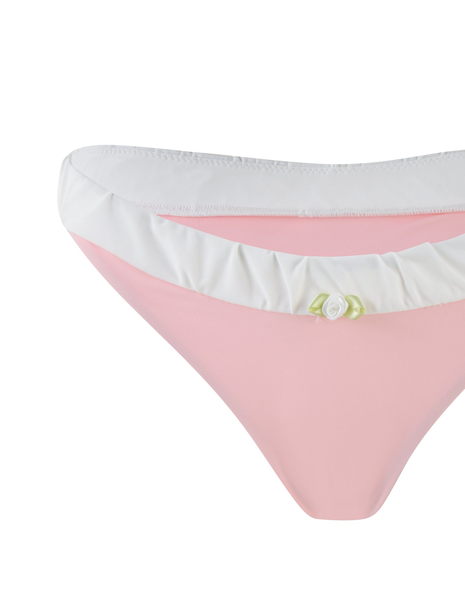A detailed image featuring the AMARAN BIKINI BOTTOM - PINK from TIGERMIST displays its cheeky cut in pastel pink, adorned with a white ruffle trim along the waistband and accented by a delicate white flower on the front. This image emphasizes the stylish design elements of this swimwear piece.