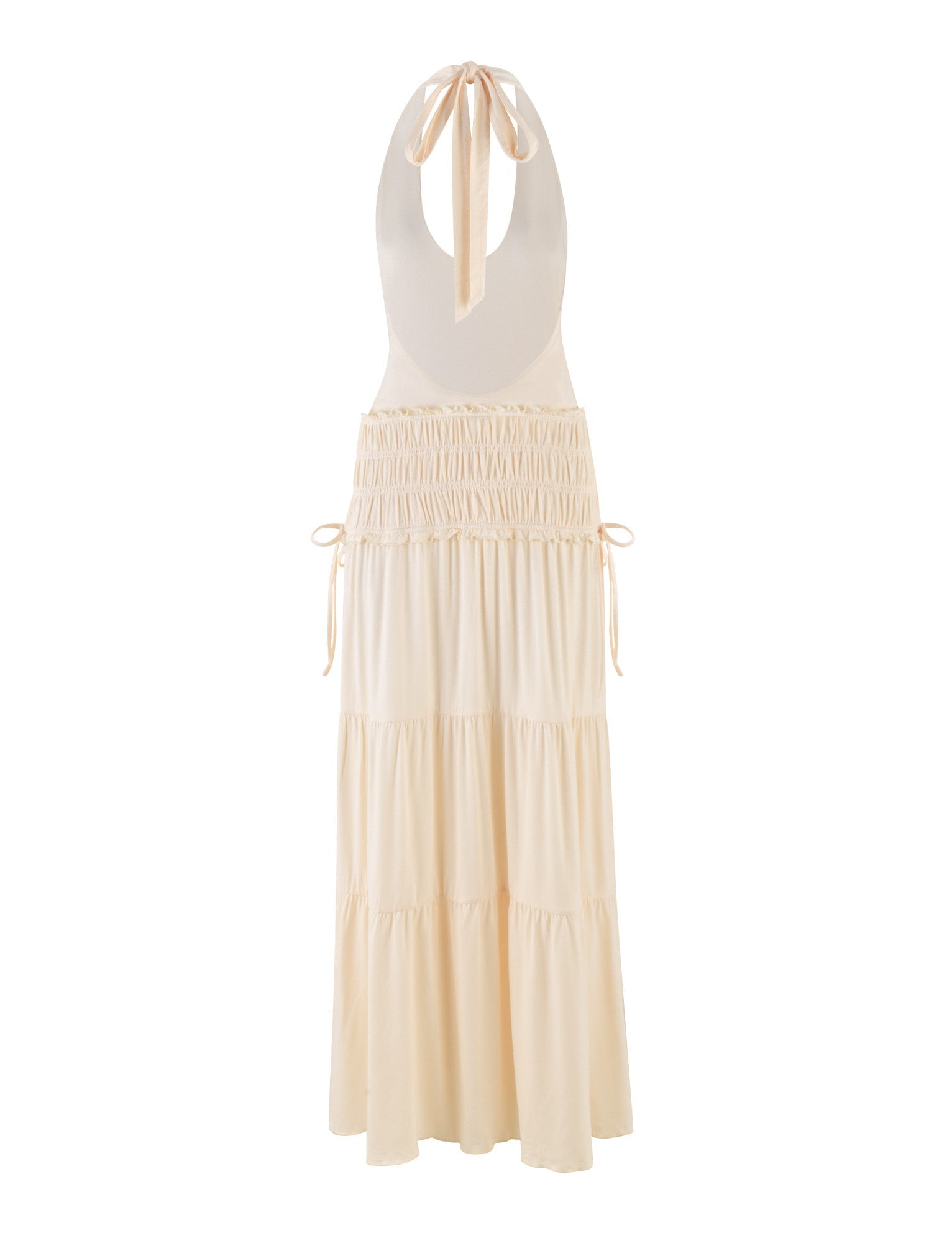 The DENALI HALTER DRESS - NEUTRAL : BONE by TIGERMIST is a cream sleeveless maxi dress in buttery jersey, with an open back, neck tie closure, gathered waist with side ties, and a tiered flowing skirt.