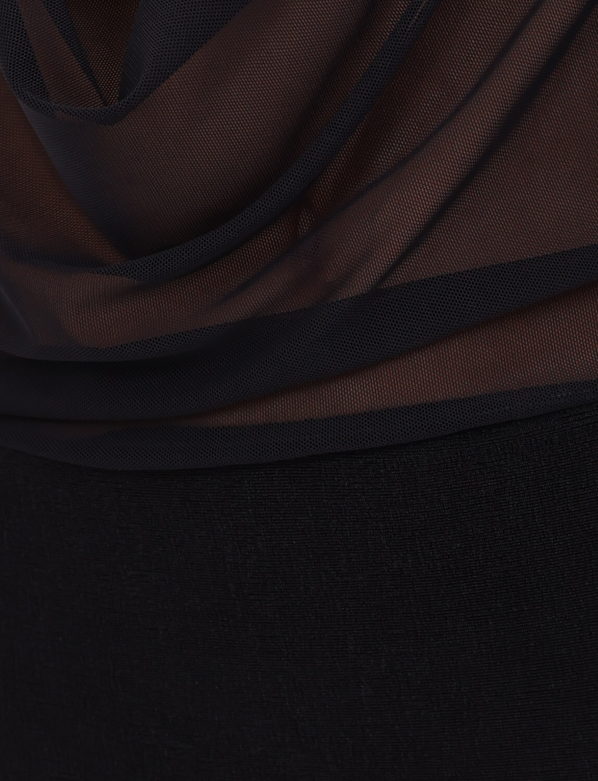 A close-up of the MAKENA TWO-PIECE DRESS - BLACK by TIGERMIST shows sheer black mesh fabric layered over an opaque, textured material for a striking semi-transparent effect.