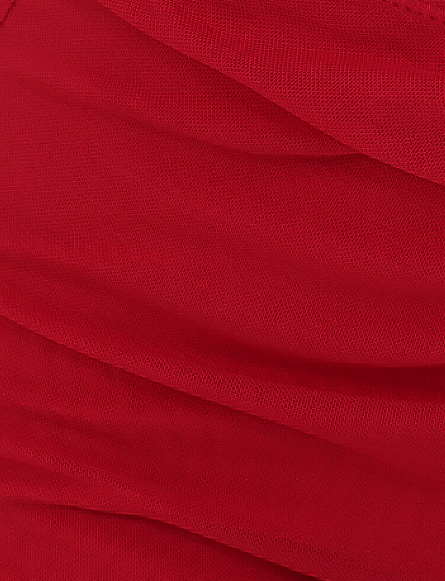 Close-up of ZAFIRA SHORT - RED by TIGERMIST, featuring a bright red hue with a textured weave and folds, forming diagonal lines and soft shadows on the high-stretch fabric.