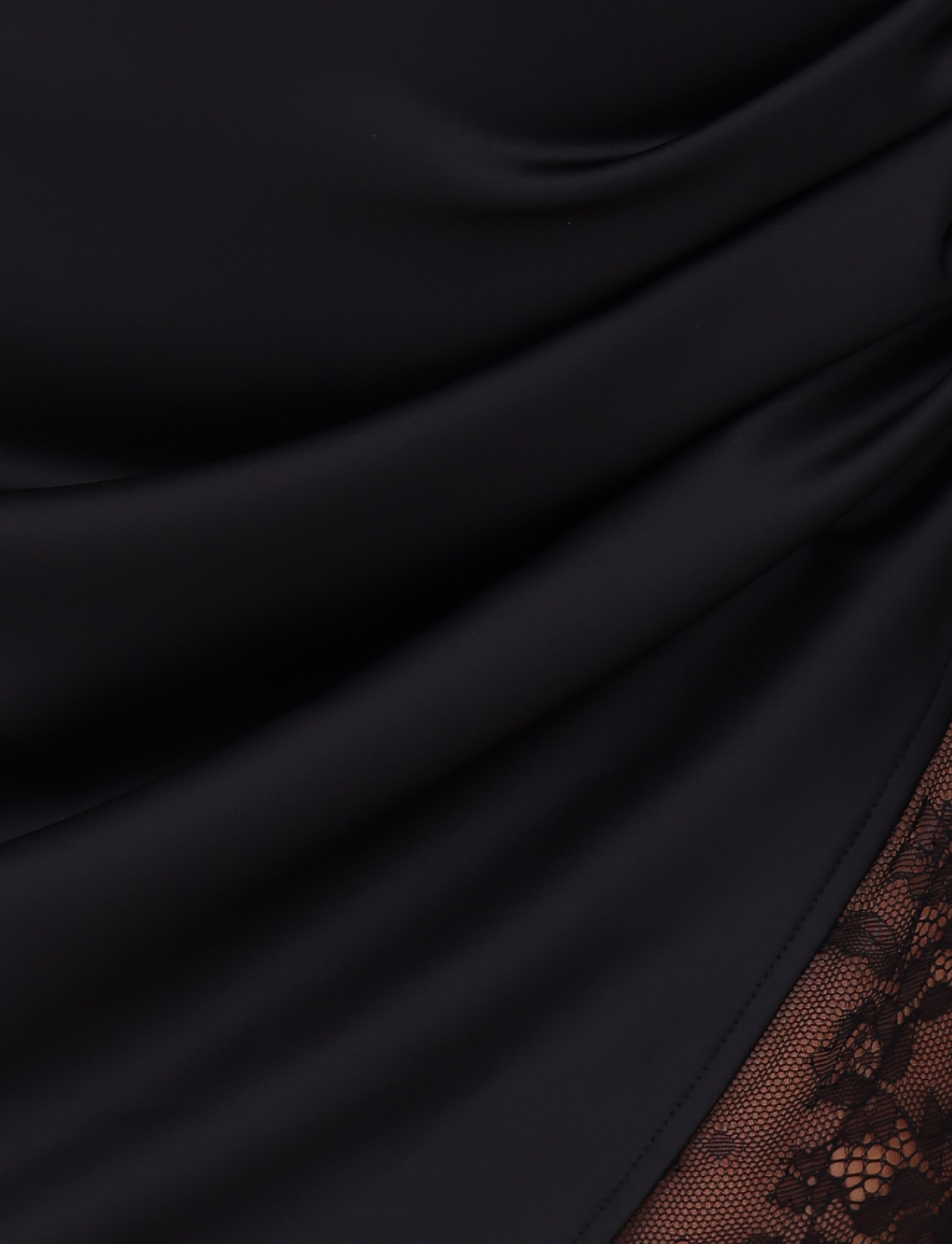 Close-up of the TIGERMIST BEXLEY MINI DRESS in black, featuring smooth satin fabric with gentle folds and a brown floral lace panel visible in the bottom right corner.