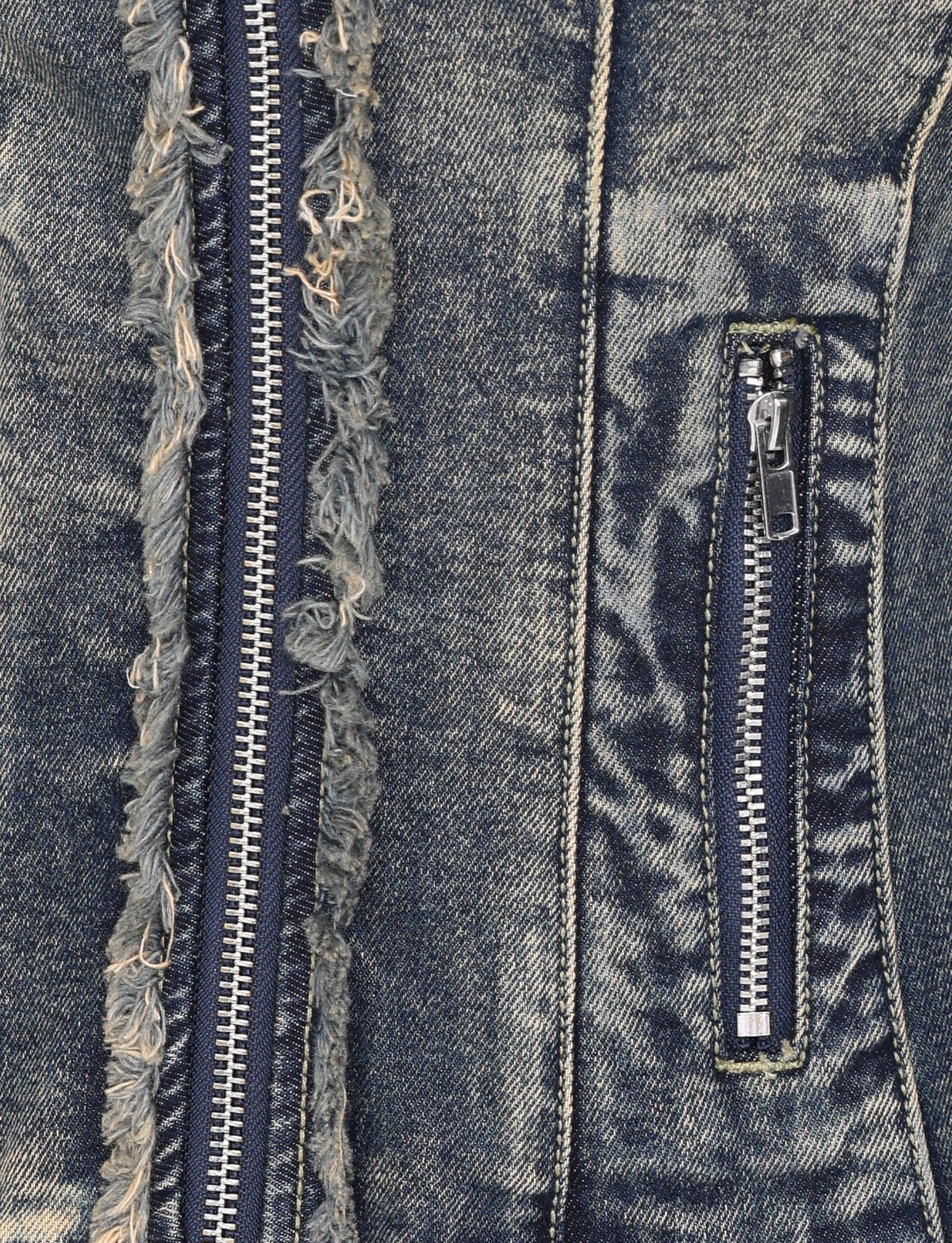 Close-up of the OPHELIE JACKET - BLUE by TIGERMIST, featuring vintage wash denim with two zippers—one vertical with frayed edges and one smaller on the pocket—showcasing its textured, worn details.