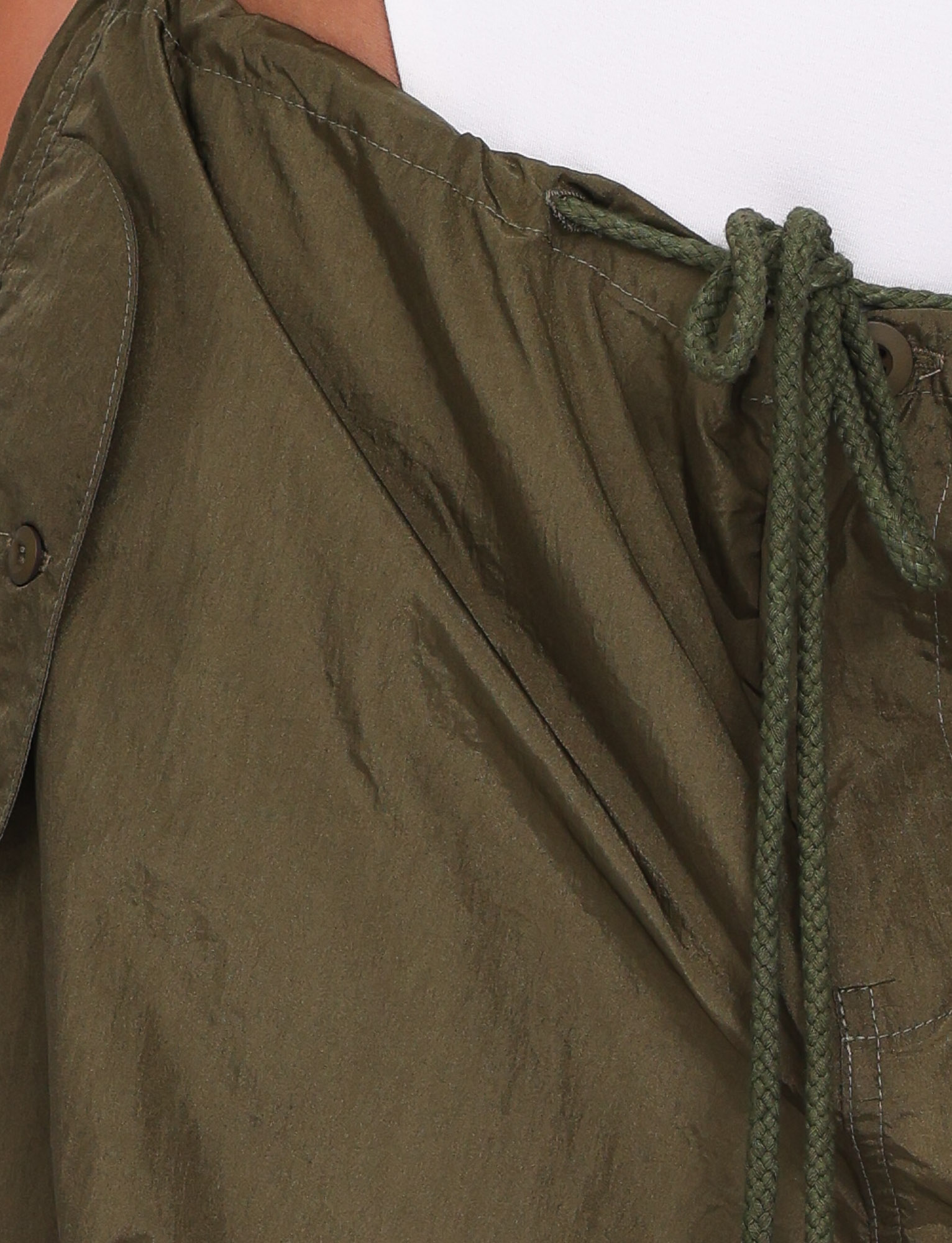 Close-up of the TIGERMIST VIOLETTE PANT in Khaki Green, featuring a drawstring and button detail. The fabric is slightly crinkled with visible stitching for adjustable sizing, shown against a pale background.