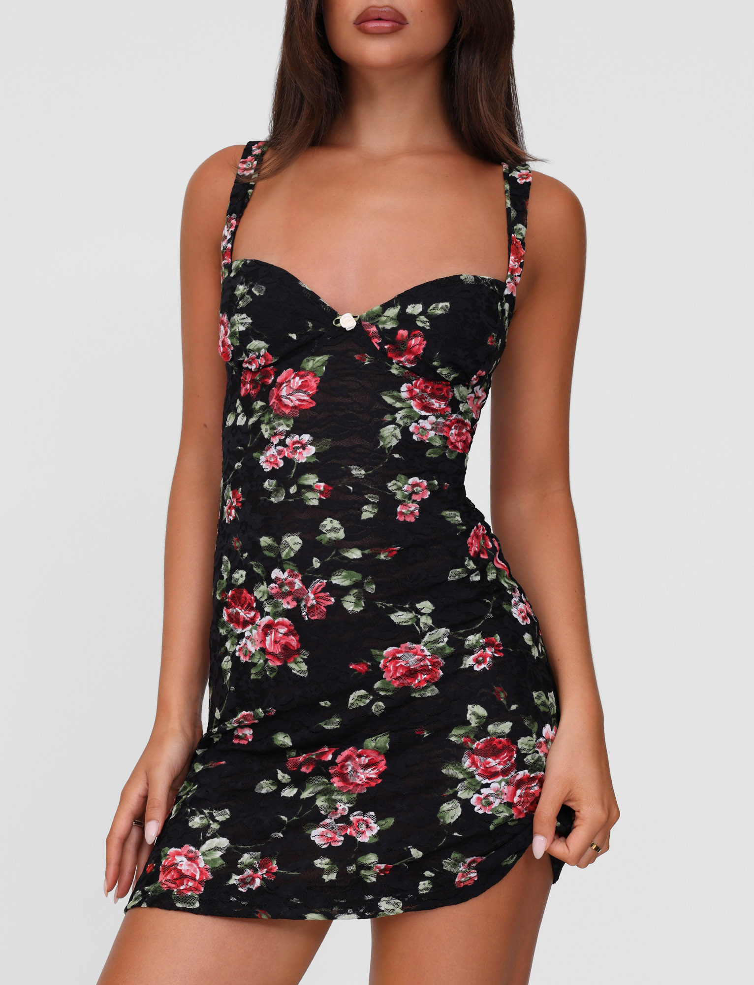 Model wears the TIGERMIST ANDEE MINI DRESS - BLACK : FLORAL : BLACKROSE, a fitted sleeveless mini with red and pink rose prints, thin straps, and a sweetheart neckline. She poses with one hand by her side against a plain background.