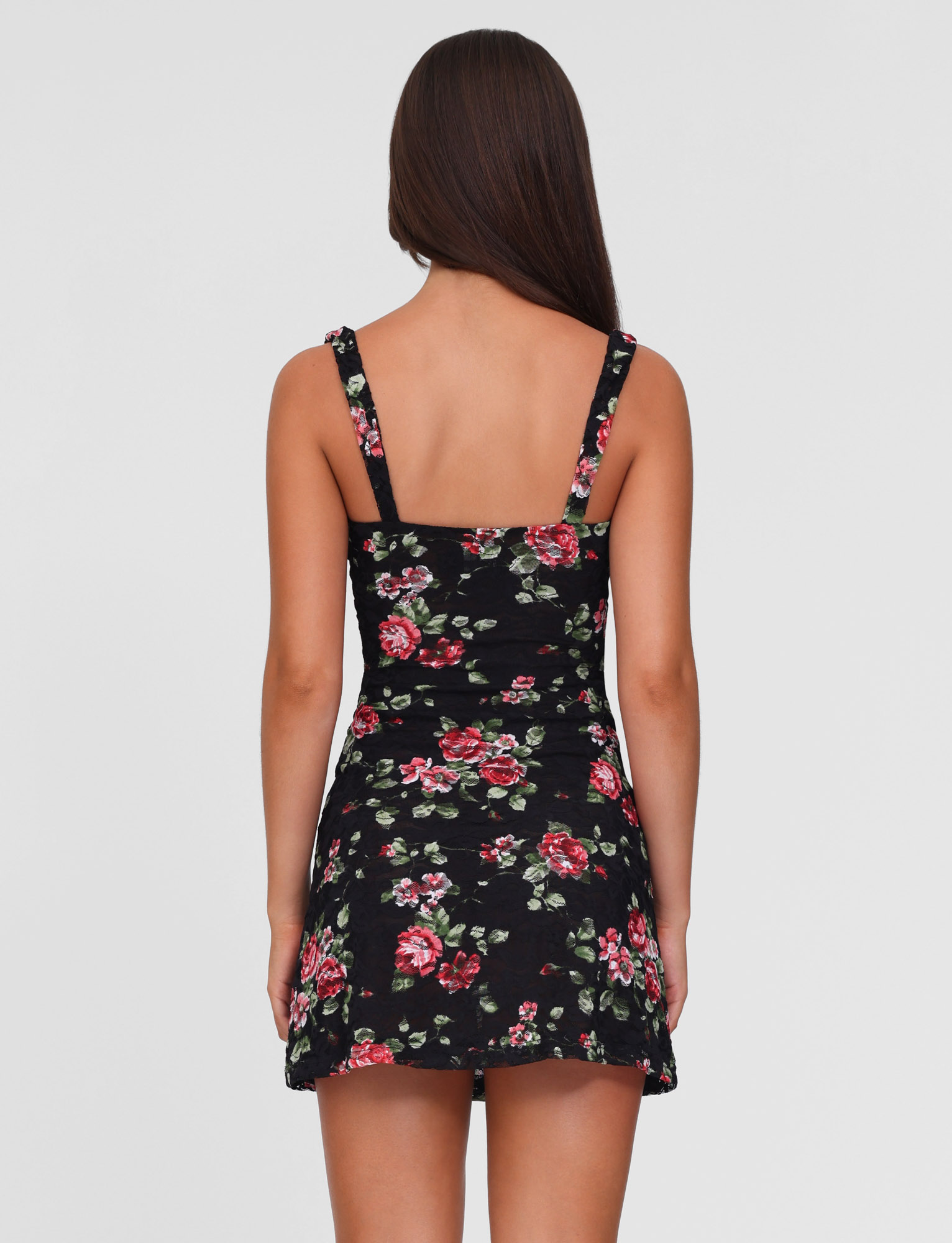 A woman with long brown hair stands with her back to the camera, wearing the TIGERMIST ANDEE MINI DRESS in BLACKROSE floral print. The background is plain white.