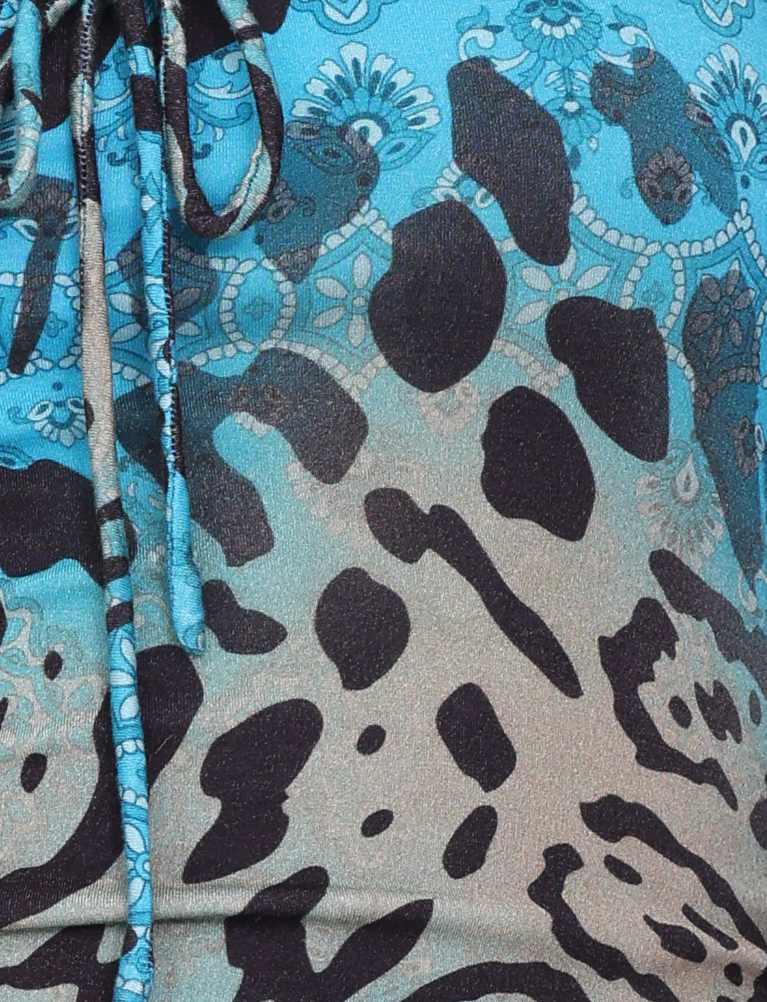 Close-up of the MIRELY TOP - MULTI : LEOPARD SWIRL by TIGERMIST, showcasing buttery jersey fabric with blue and beige abstract leopard spots, floral motifs, and two drawstrings on the left side.