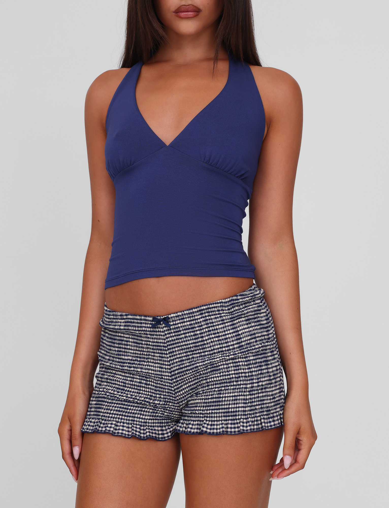 A woman wearing the TIGERMIST MERIAL TOP in denim blue stands against a plain background, her arms relaxed by her sides.