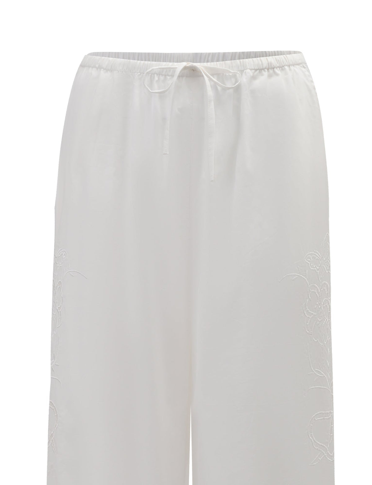 The CRESSY PANT - WHITE by TIGERMIST features a wide-leg, full-length cotton design with an elastic waistband and drawstring, soft lightweight fabric, and subtle floral embroidery along the sides.