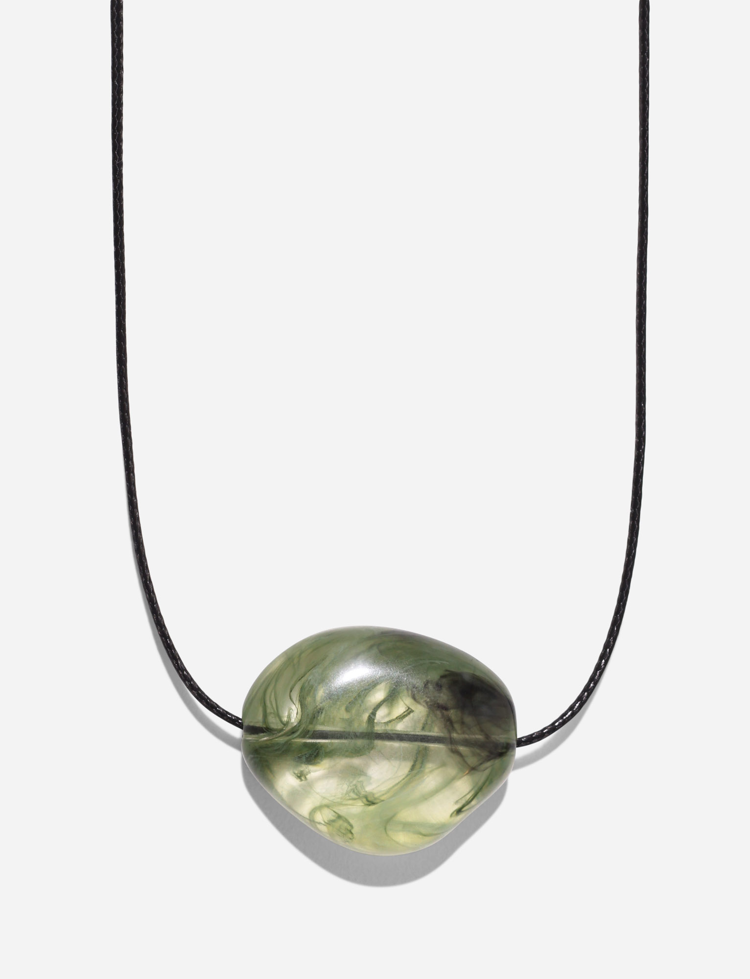 The TIGERMIST SOLENE NECKLACE - GREEN features a simple black woven cord with an oval, translucent green stone pendant adorned with swirling patterns, shown on a white background.