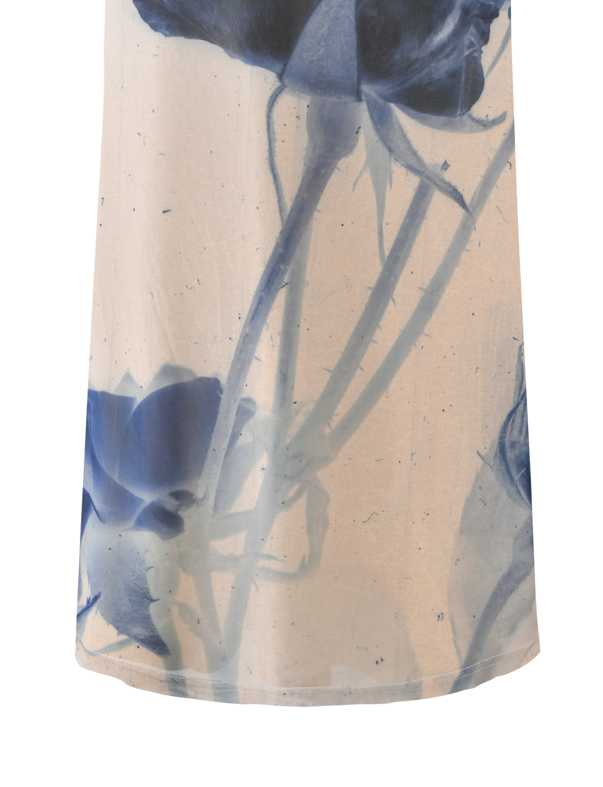 A close-up of the TIGERMIST JANIS MAXI SKIRT - INDIGO FLORAL shows semi-transparent fabric with large blue floral designs and stems on a light beige background.