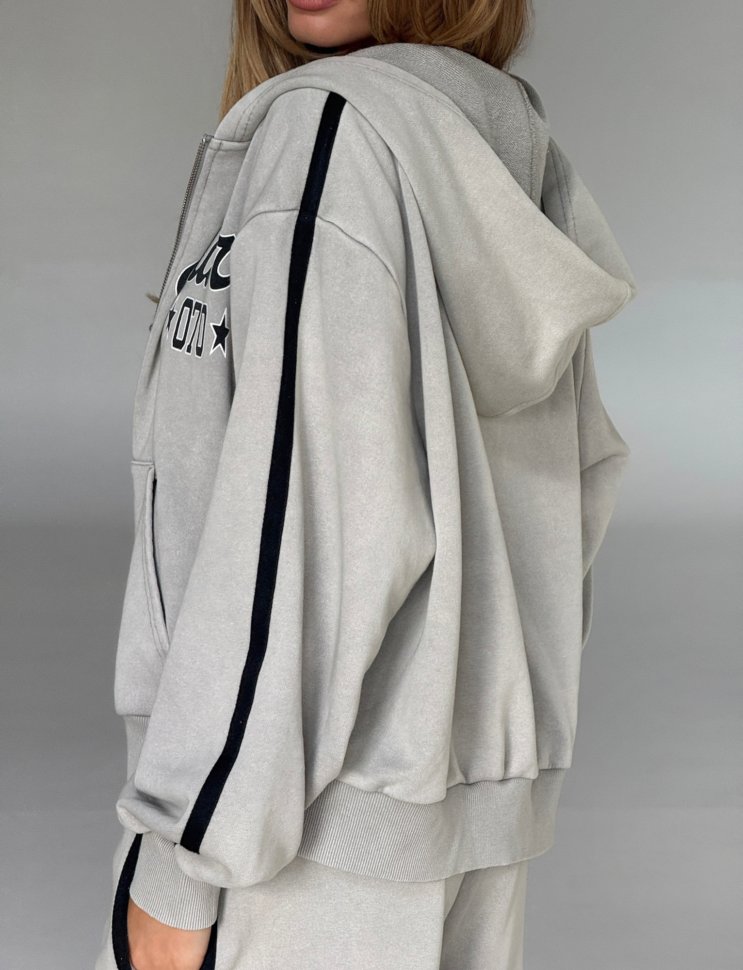 A person wears the TIGERMIST PAYTON HOODIE in stone with matching pants, standing sideways against a plain gray background.