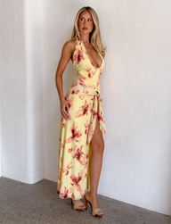 A woman in the TIGERMIST ALLEGRA MAXI DRESS in yellow watercolour floral print, featuring a plunging halter neckline.